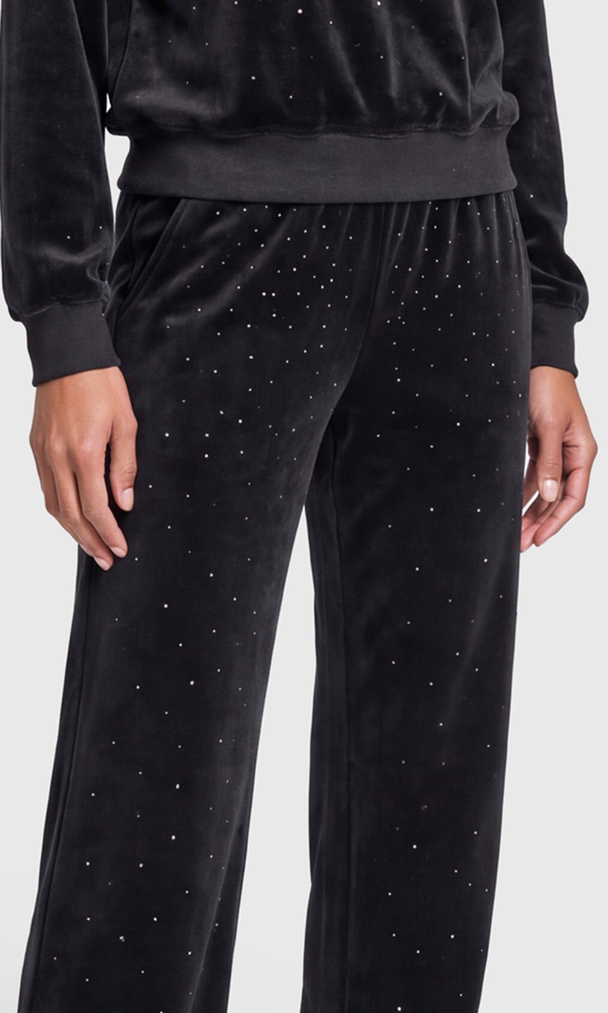 Close-up of a black velvet long-sleeve hoodie and matching pants, both decorated with small silver rhinestone accents.