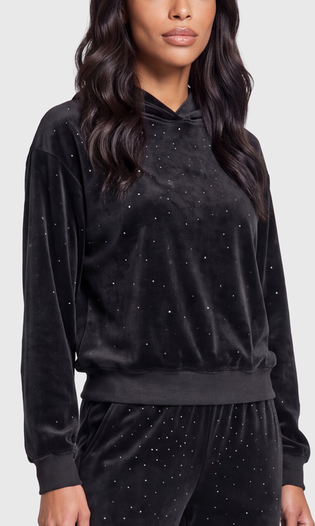 Close-up of a black velvet long-sleeve hoodie and matching pants, both decorated with small silver rhinestone accents.
