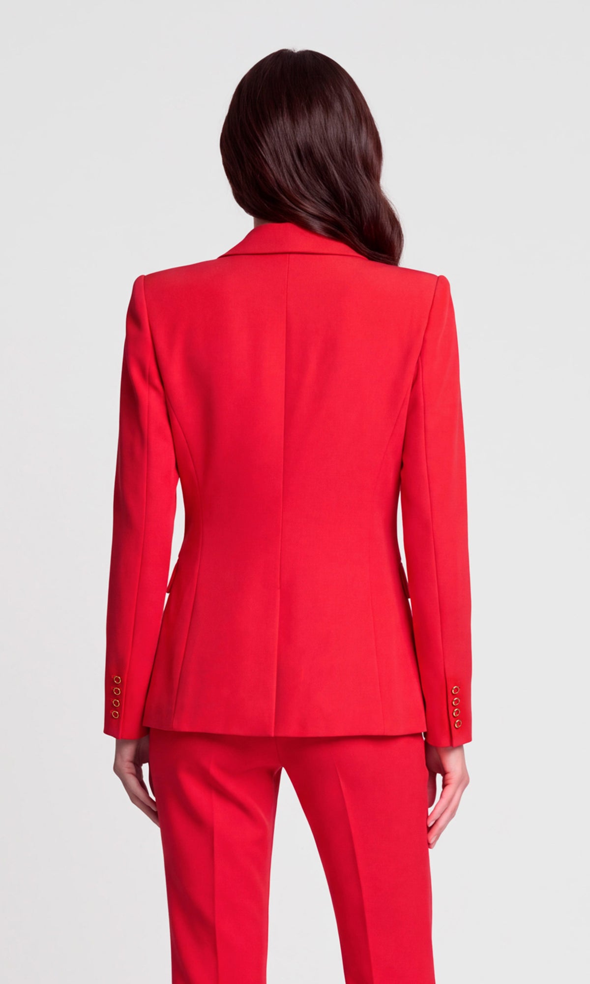 A woman shown from the back wearing a bright red tailored blazer and matching trousers.