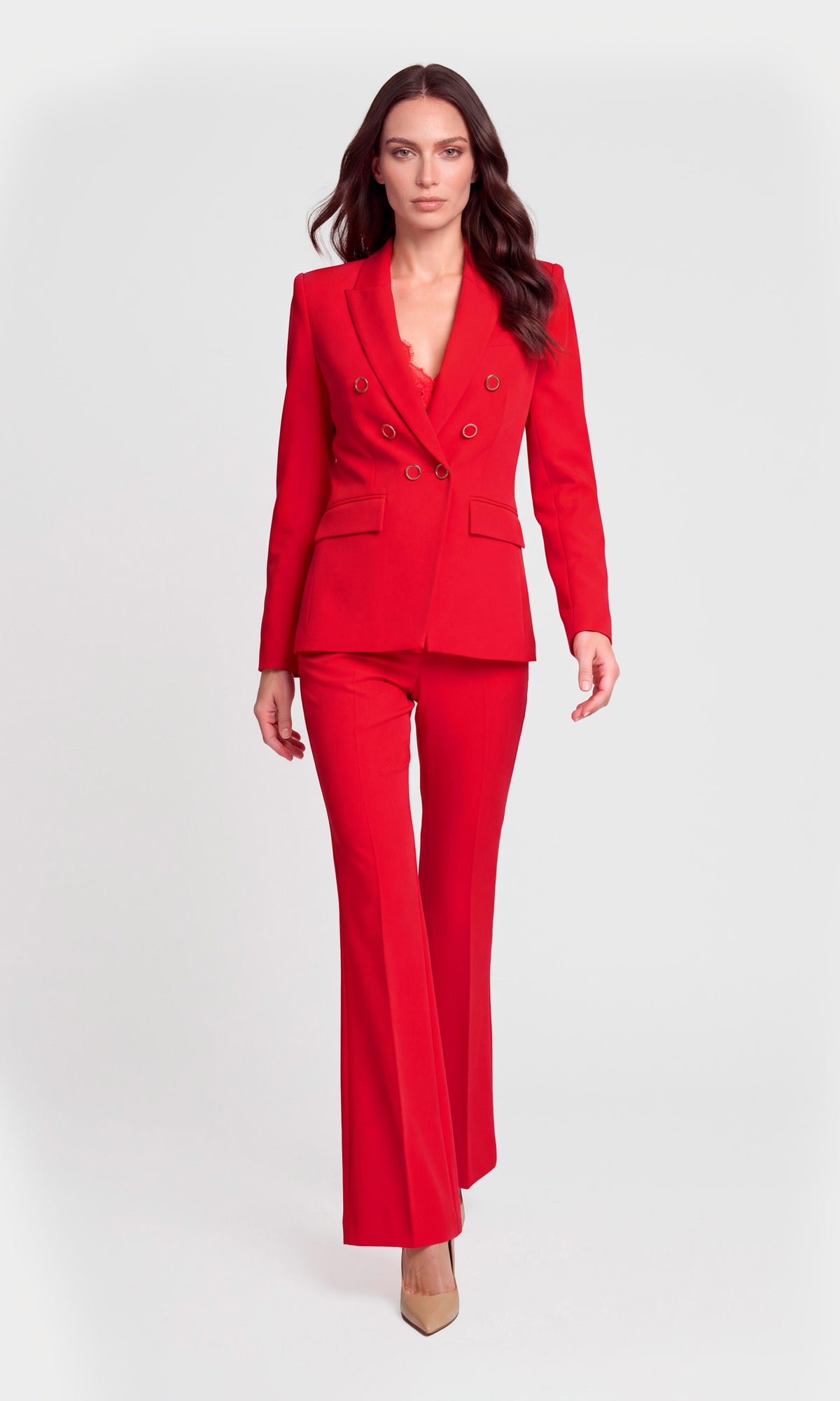 A woman modeling a bright red double-breasted blazer and matching flared trousers.