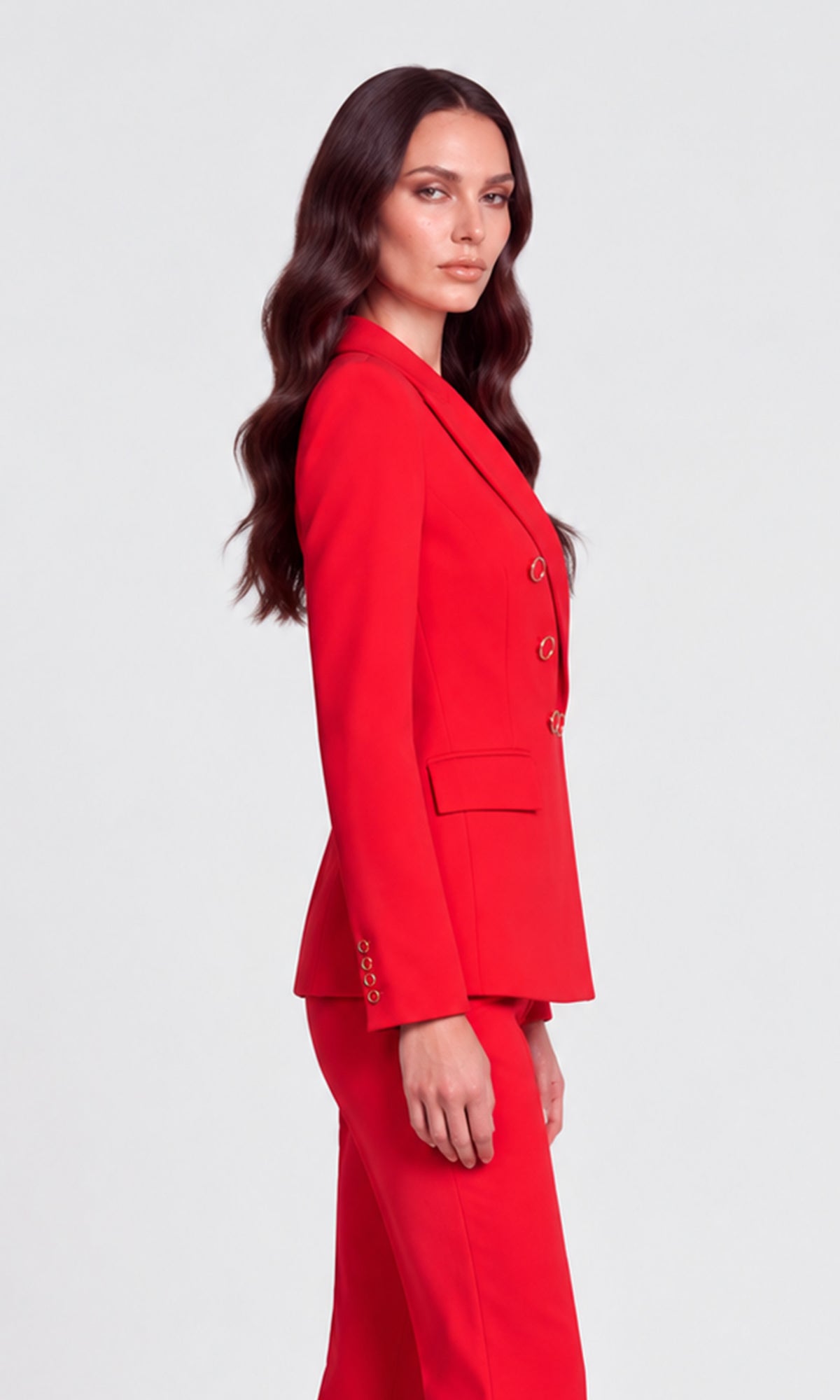 A woman modeling a bright red double-breasted blazer and matching red trousers.