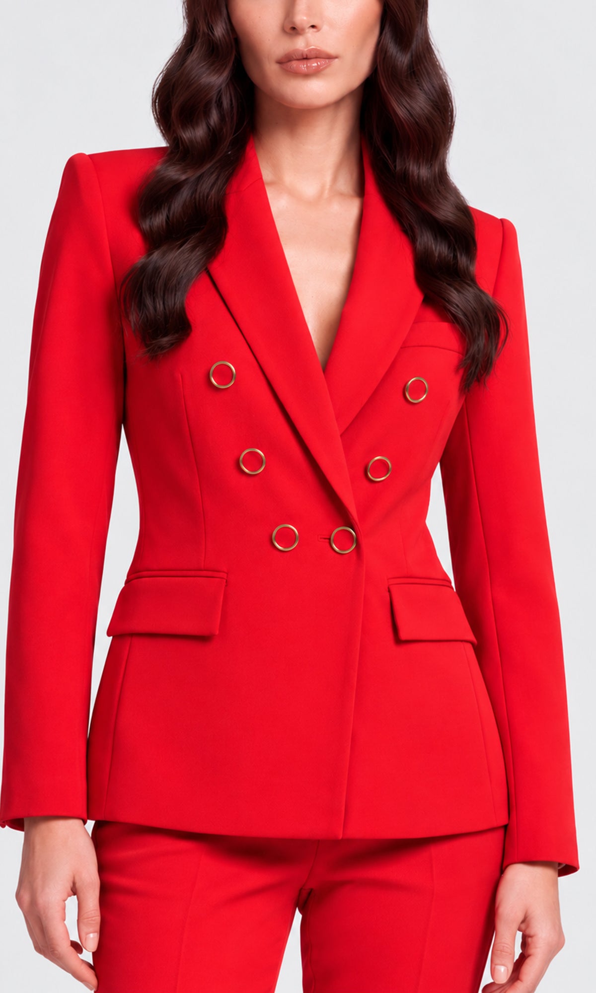A woman wearing a bright red double-breasted blazer with gold-tone ring buttons and matching red trousers.