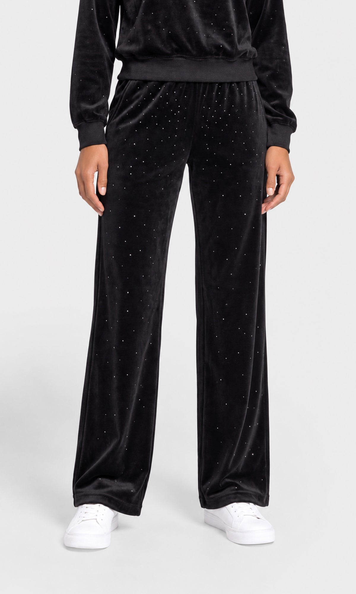 Black velvet wide-leg pants with small silver rhinestone embellishments, shown on a model wearing white sneakers.