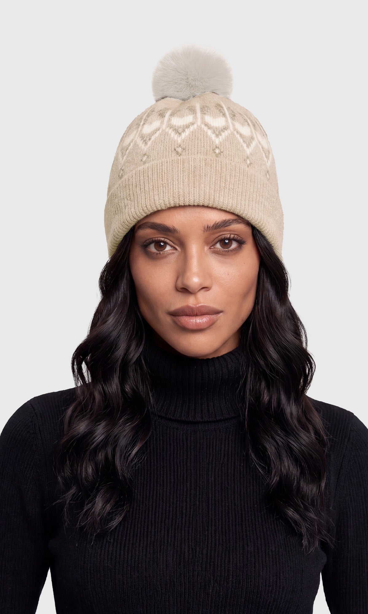 A woman wearing a beige knit beanie with a pom-pom and a black ribbed turtleneck sweater.