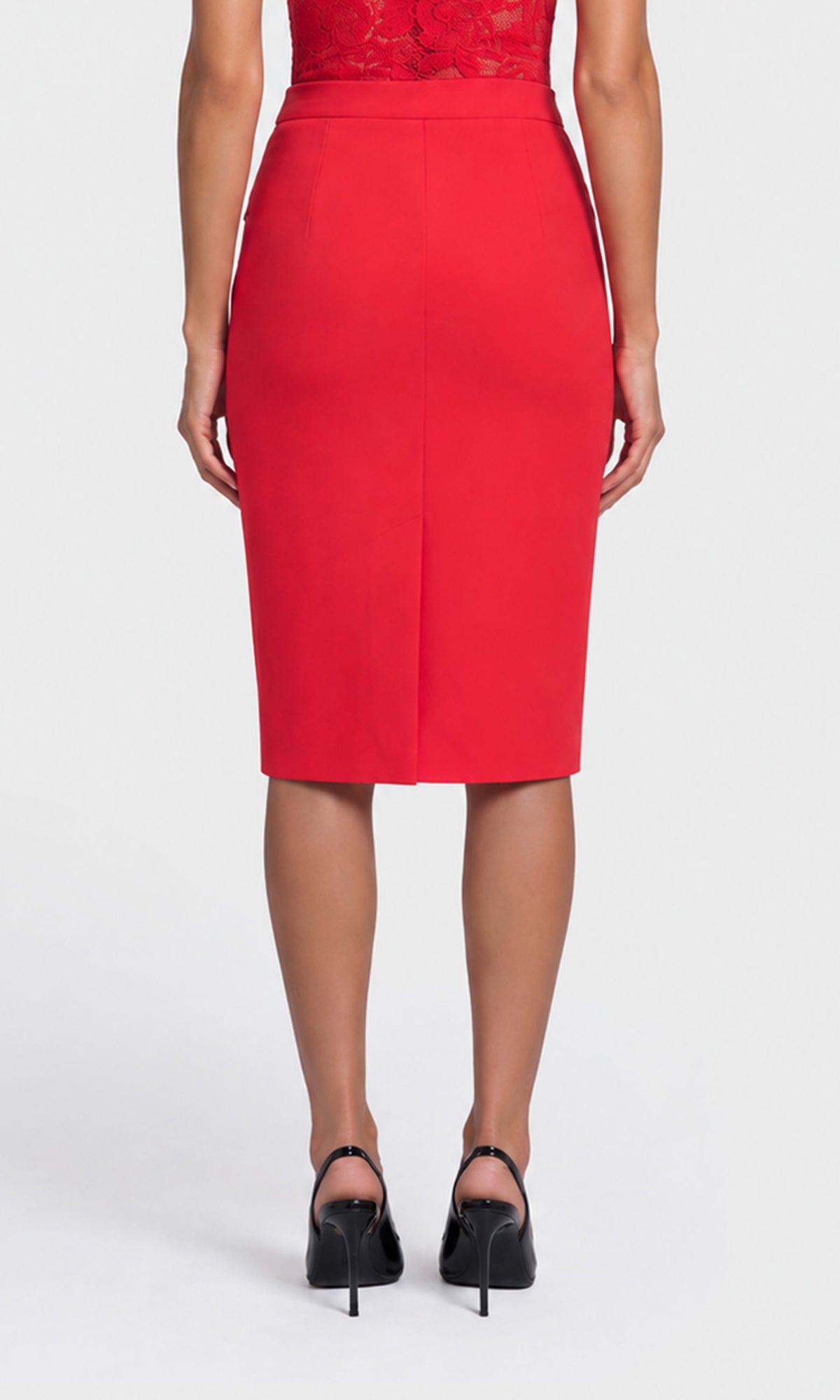 A woman shown from the back wearing a bright red knee-length pencil skirt with a front slit, paired with black high heels.