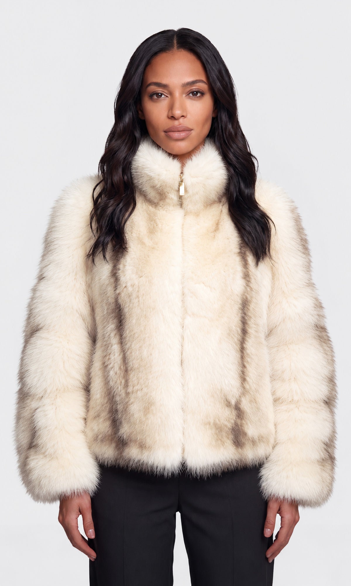 Model wearing a cream-colored faux fur jacket with a high collar and a subtle brown mottled pattern, paired with black pants.