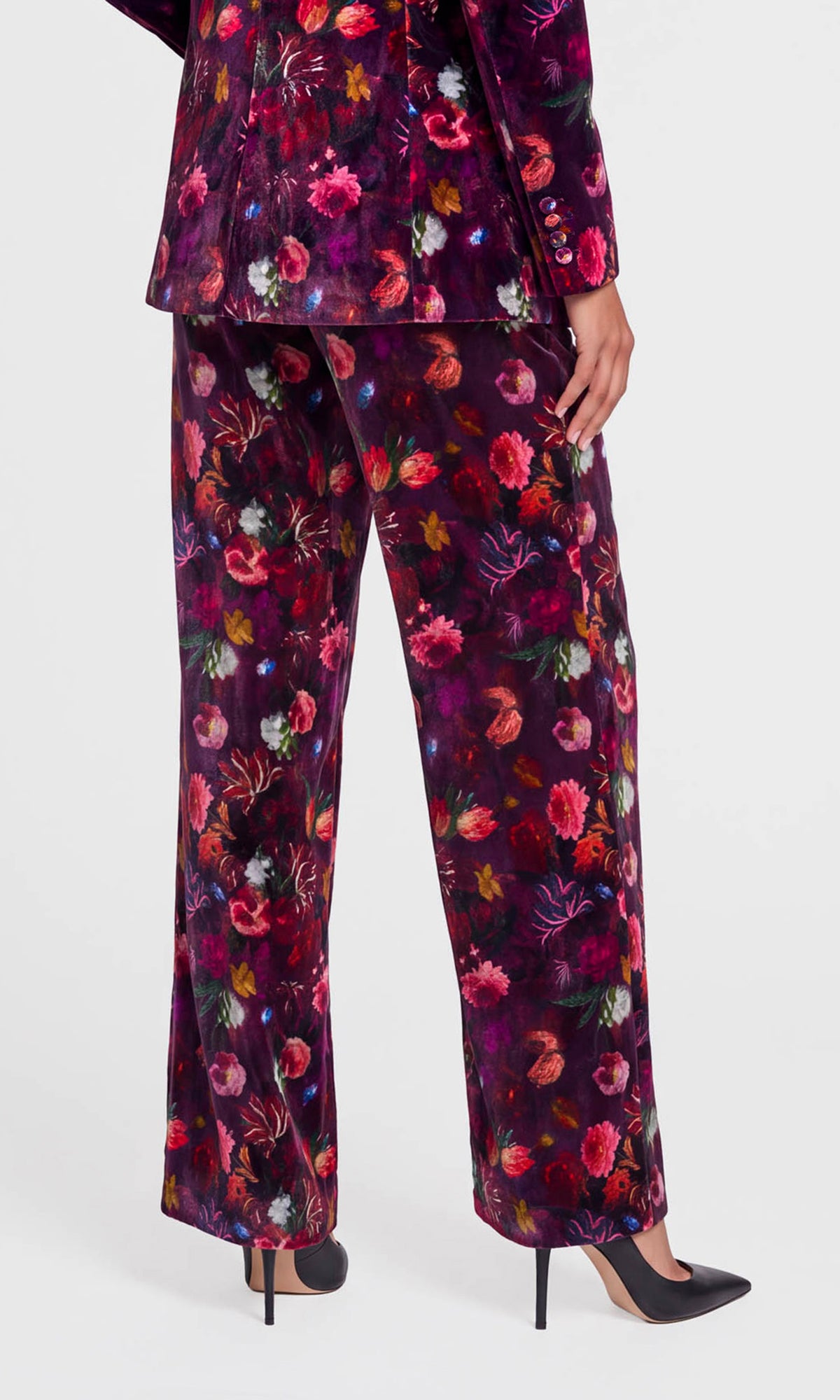 A model is shown from the back wearing a matching floral velvet pantsuit, featuring a dark purple base.