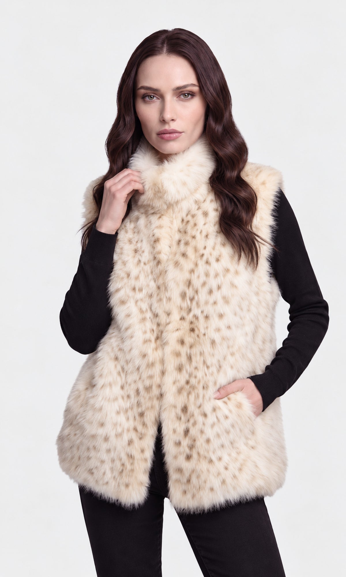 A woman modeling a sleeveless faux fur vest with a beige and cream leopard-like pattern, worn over a black long-sleeve top.
