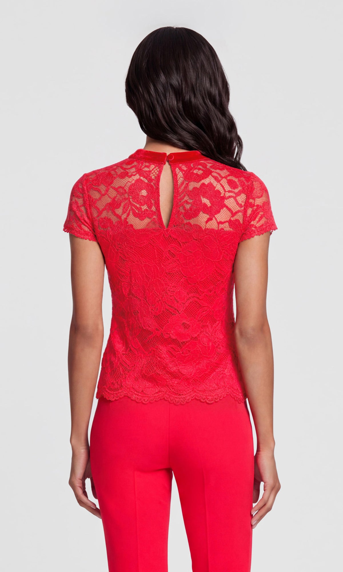 A woman shown from the back wearing a bright red lace short-sleeve top with a keyhole cutout and matching red pants.