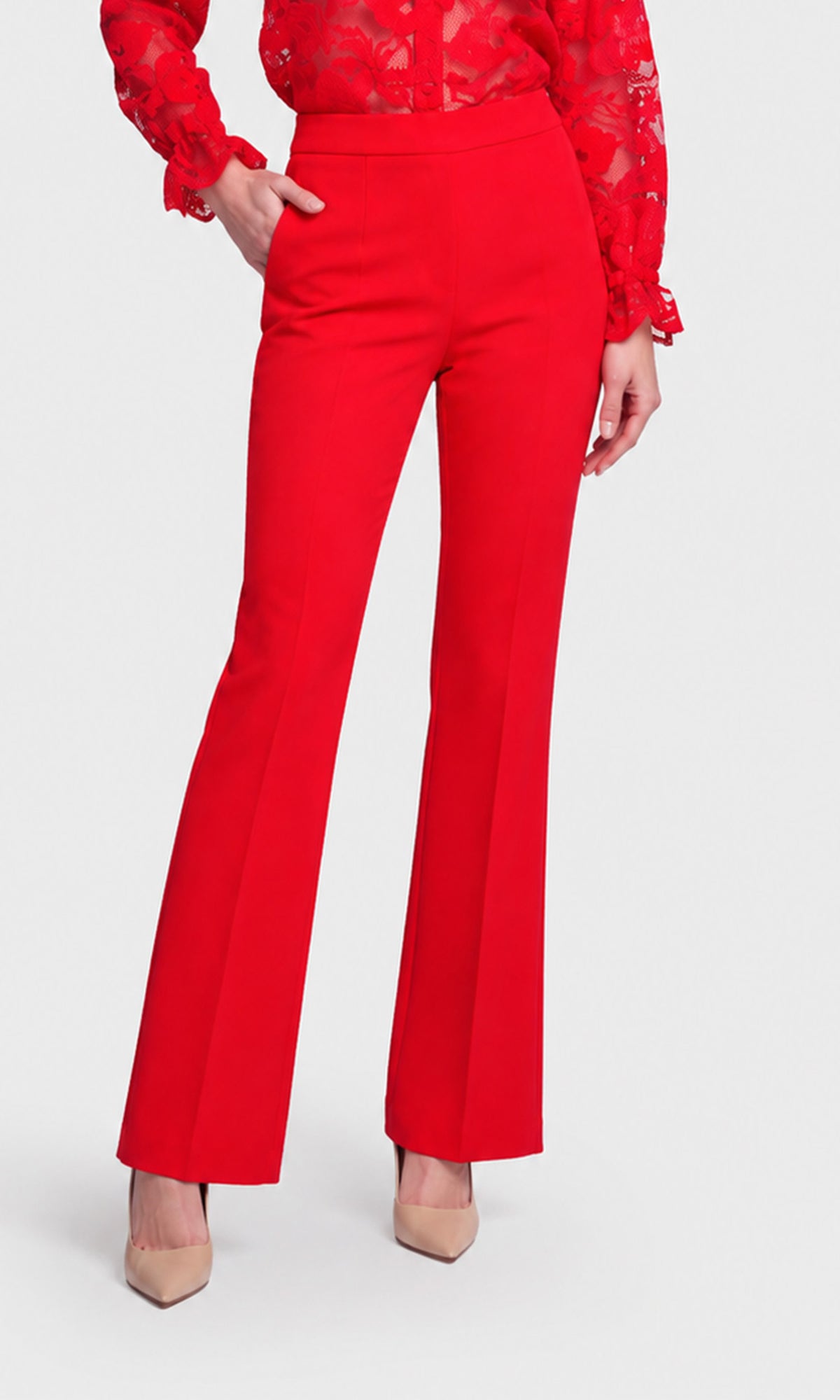 A model wearing bright red high-waisted flared trousers paired with a red lace long-sleeve top and beige pointed-toe heels.