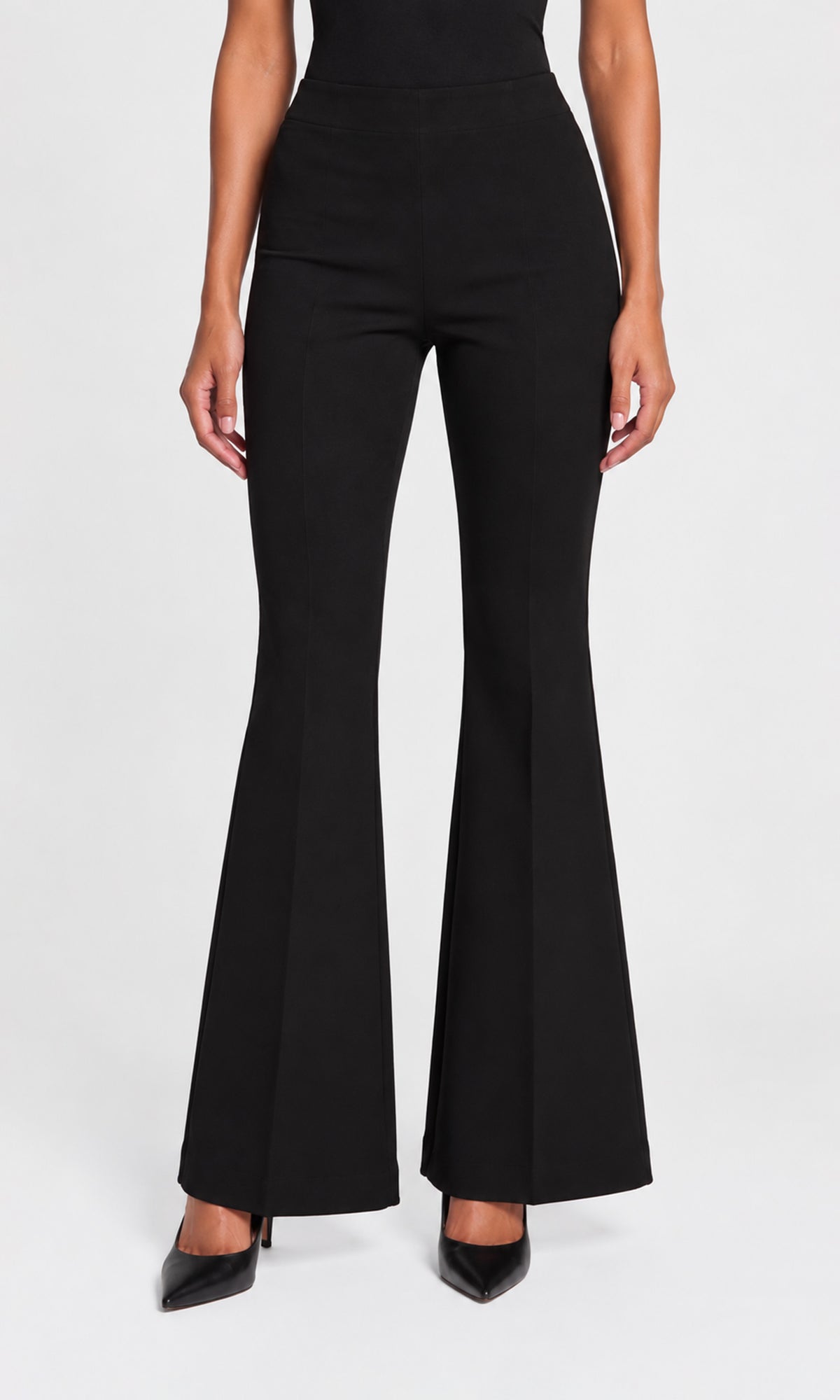 Model wearing black high-waisted flared pants with a straight waistband, paired with black pointed-toe heels.