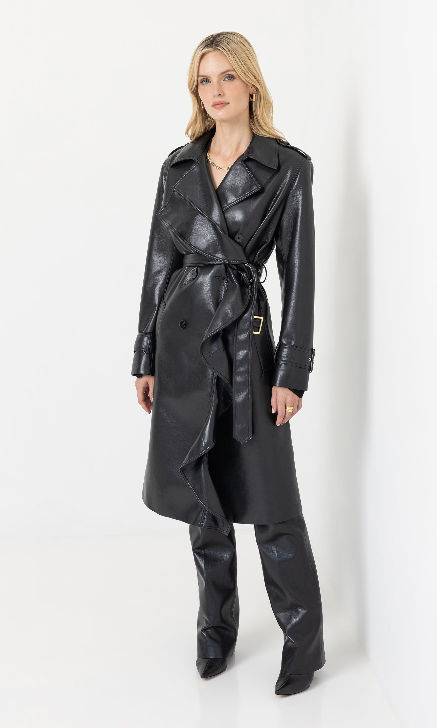 Full body front view of the hearst vegan leather trench coat styled with trousers and boots.
