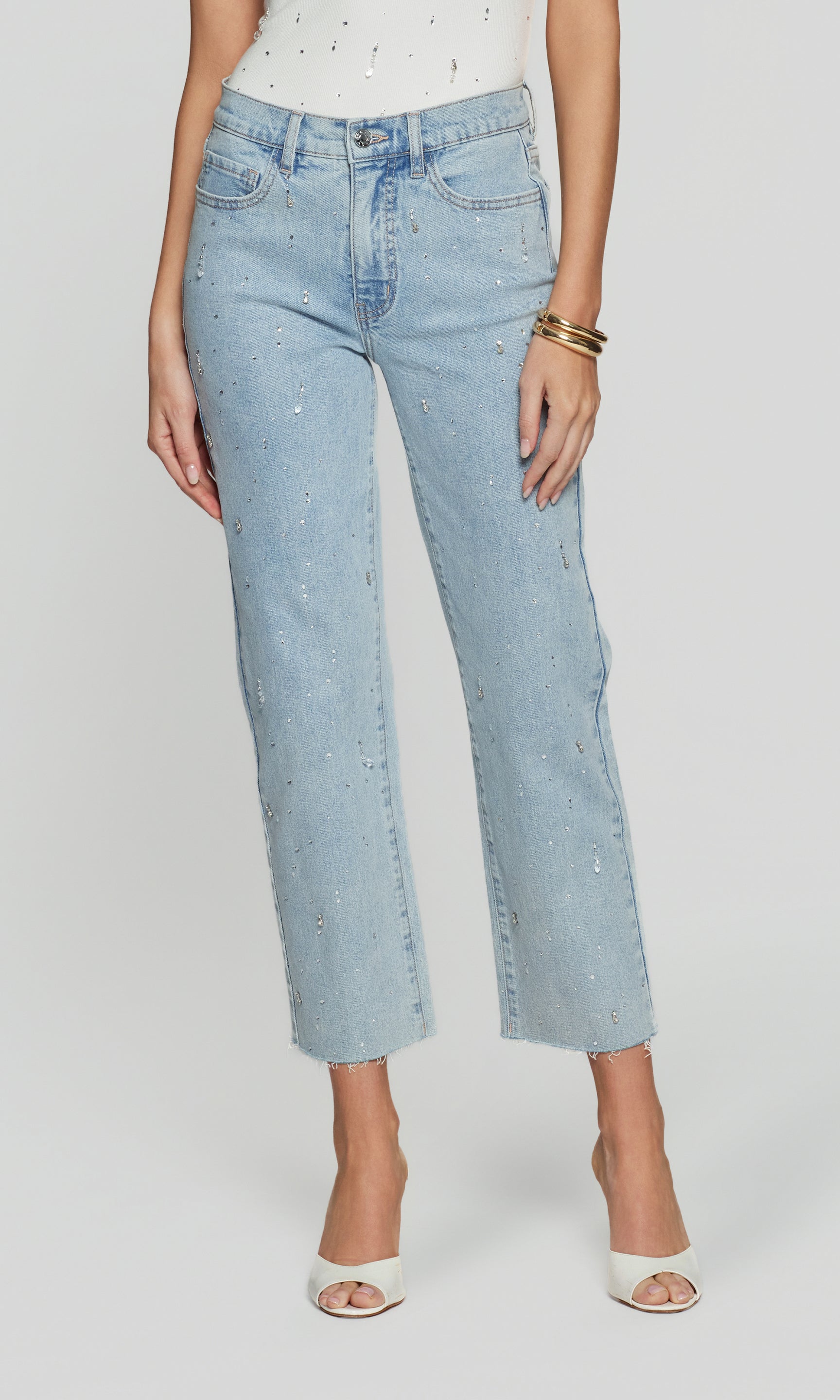 Light blue jeans with crystal embellishments worn by a person on a white background