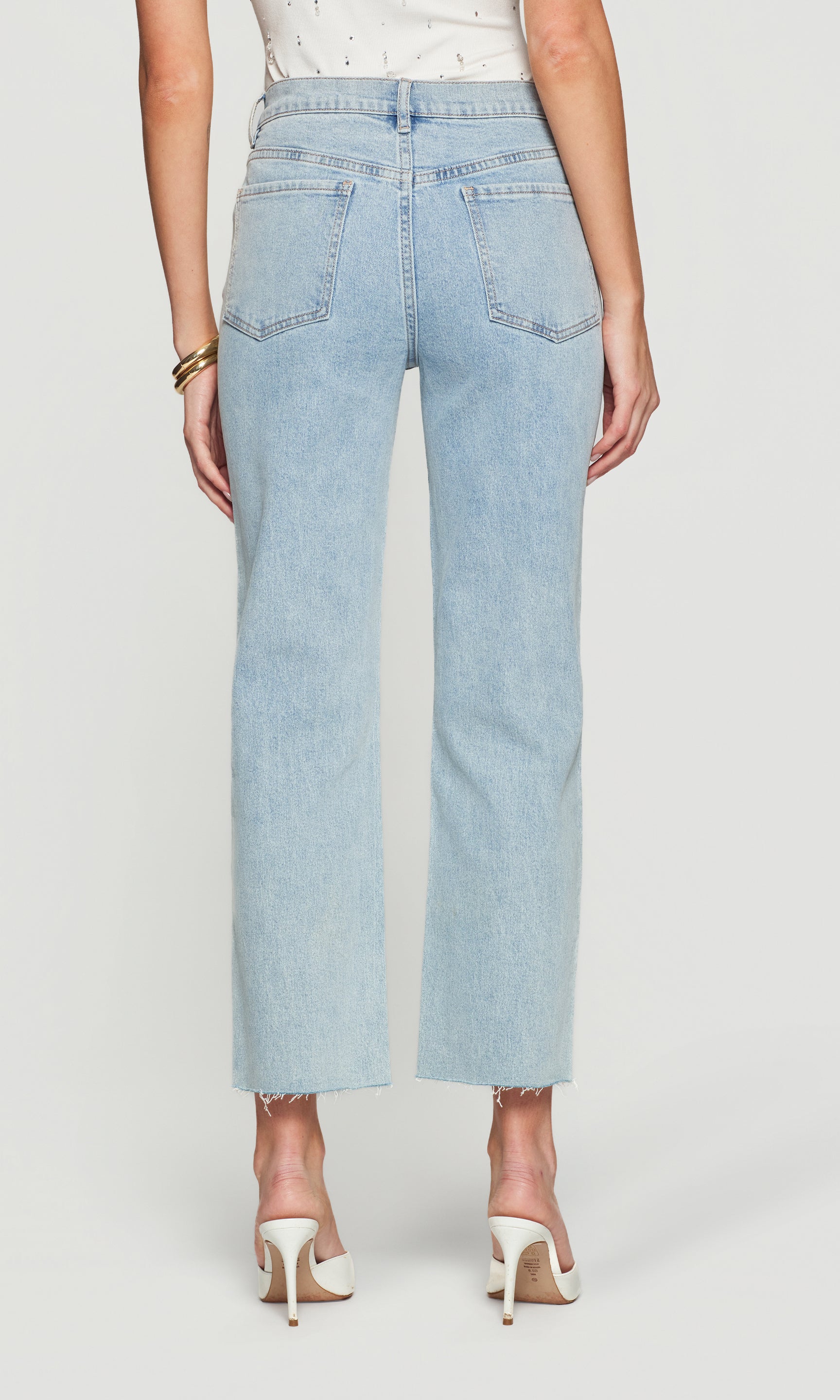 Back view of light blue jeans worn by a person on a white background