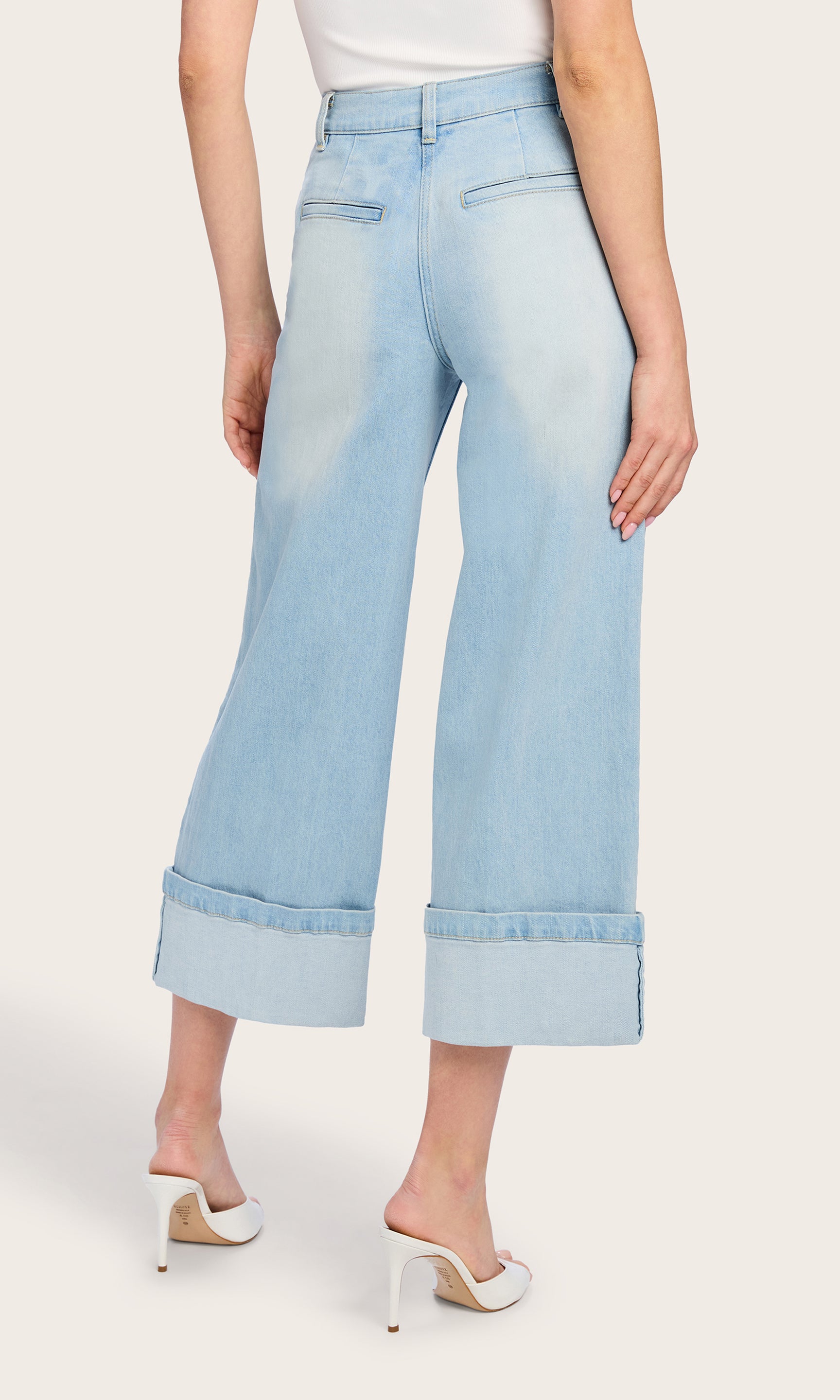 The rear view shows the model in the Eros Denim Pant, emphasizing the structured fit and back pocket detailing for a polished denim look.