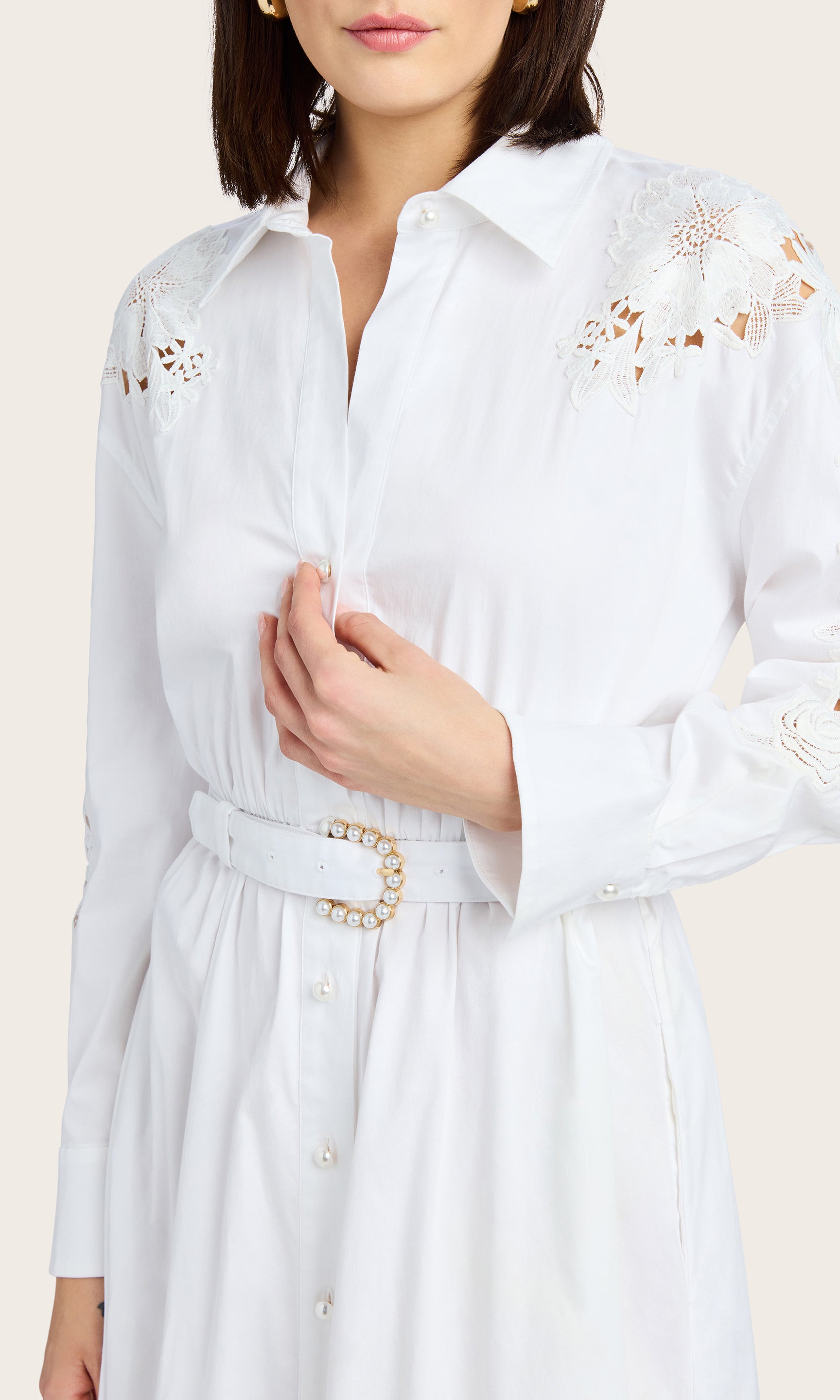 Close-up detail highlighting the lace sleeve design and pearl shank buttons on the white dress