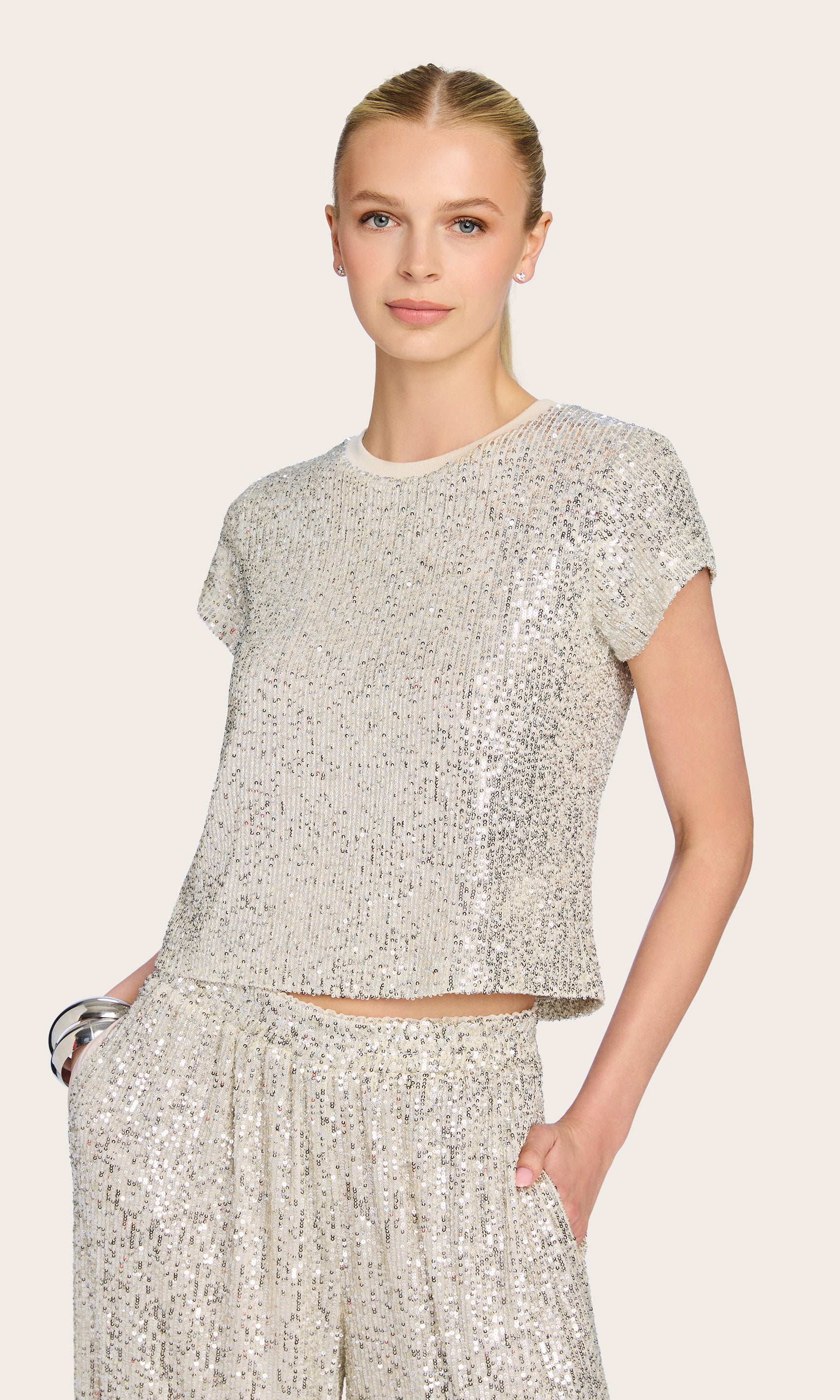 The model wears the Kai Sequin Top in silver in a front view, paired with matching sequin pants for a coordinated statement look.