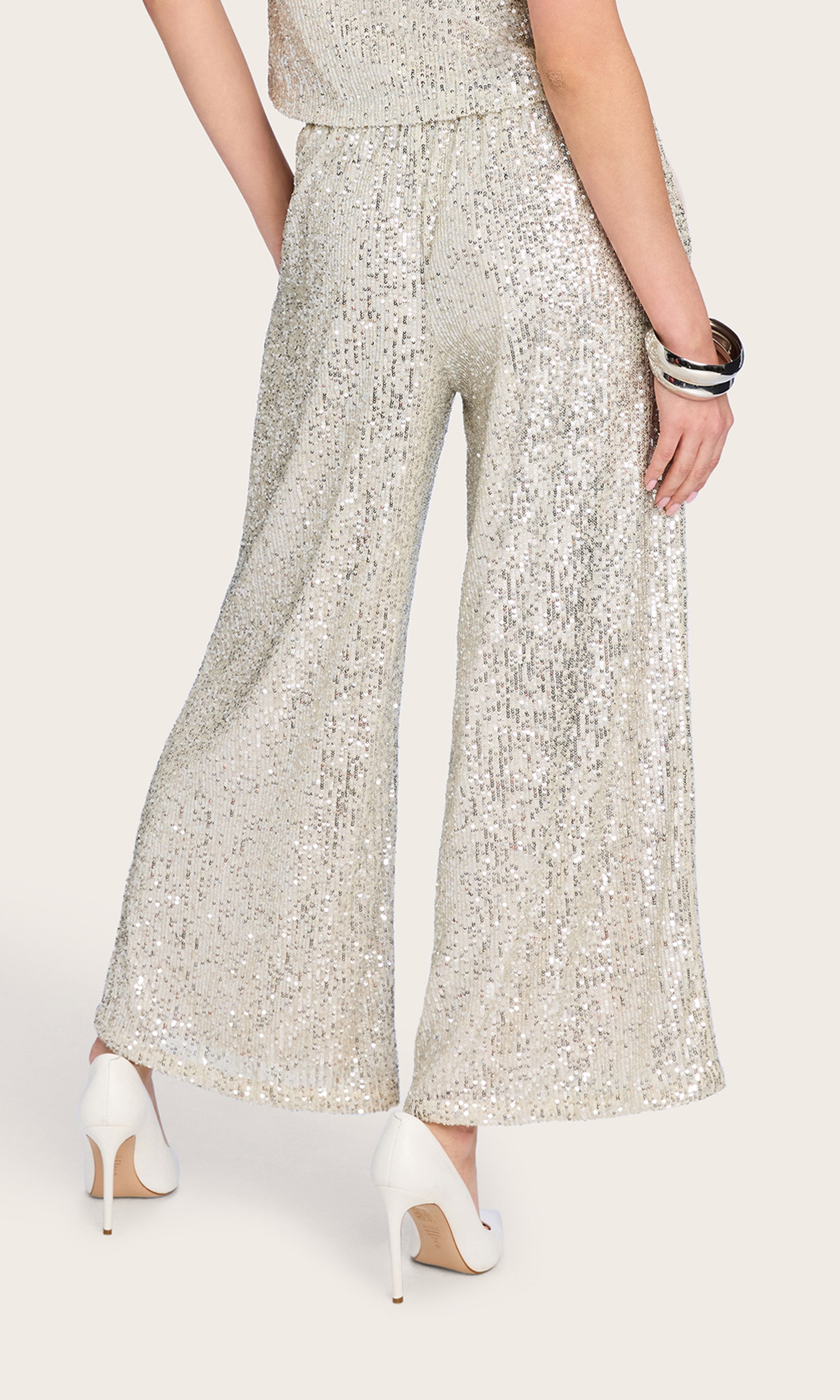 Rear view of the model wearing the Talia Sequin Pants, paired with a matching top for a sparkling, coordinated look.