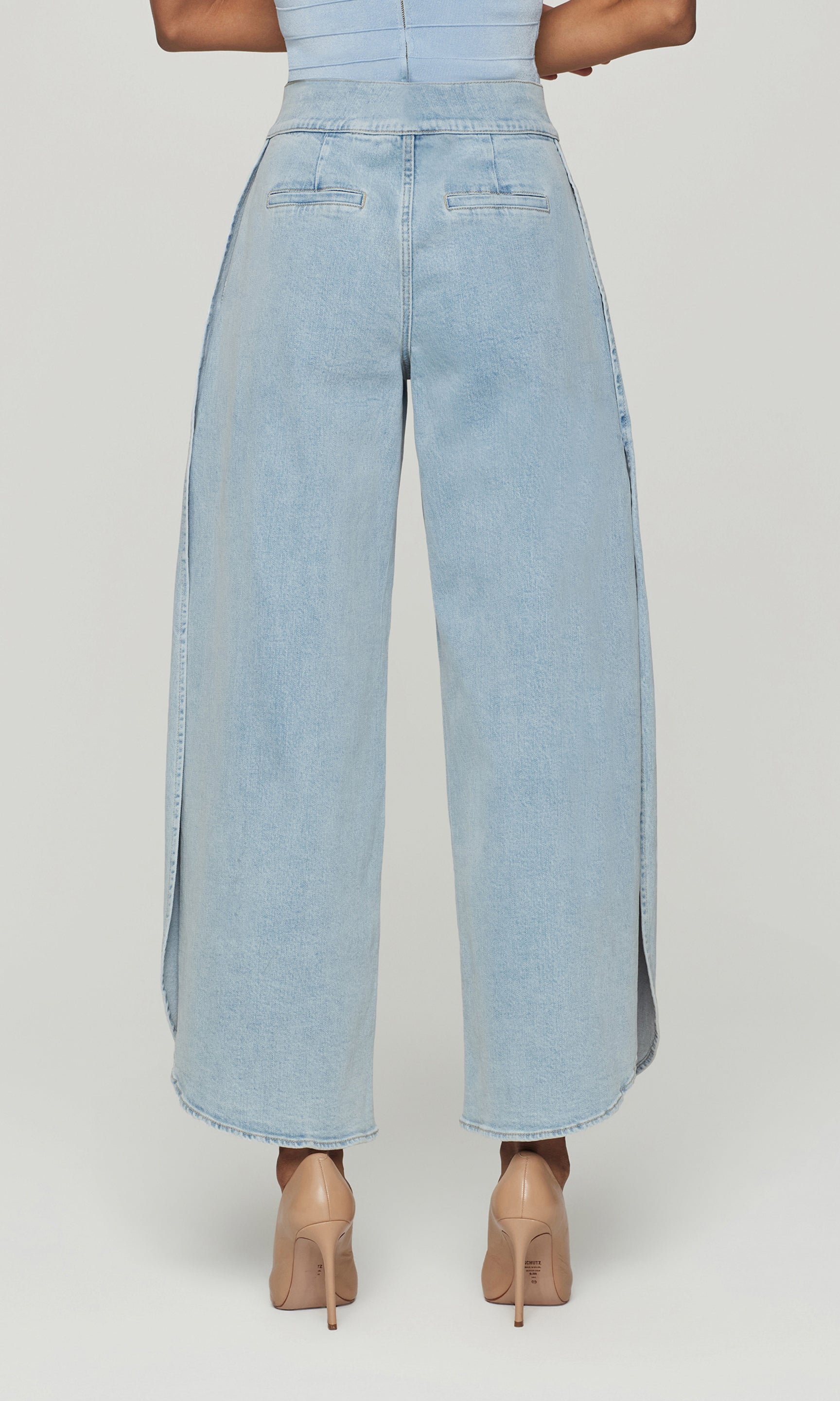 Back view of light blue denim wide-leg pants worn by a person on a white background