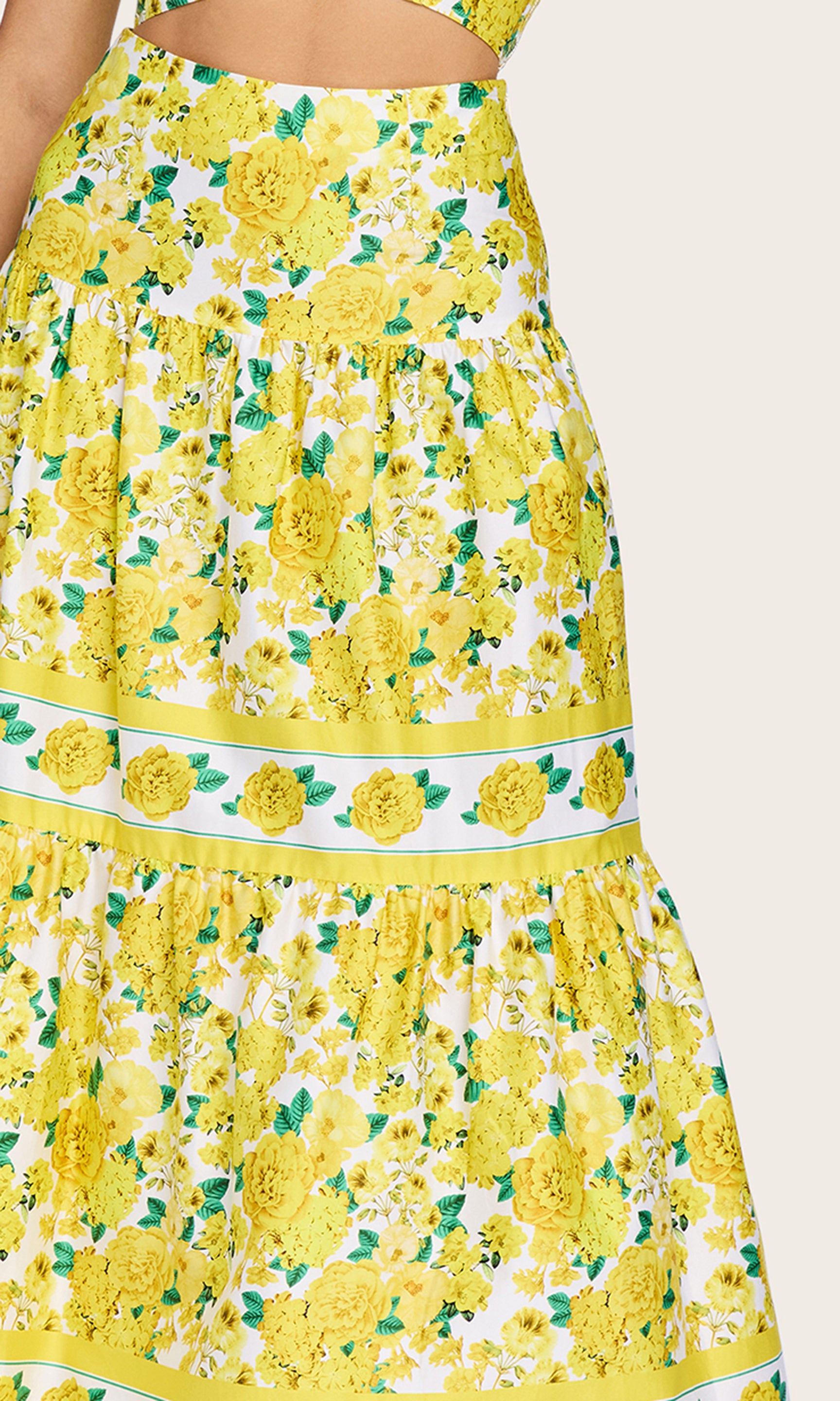 Detailed view image of the model wearing the Mondo Floral Poplin Skirt in a yellow floral print highlighting the tiered structure of this flowy maxi skirt.