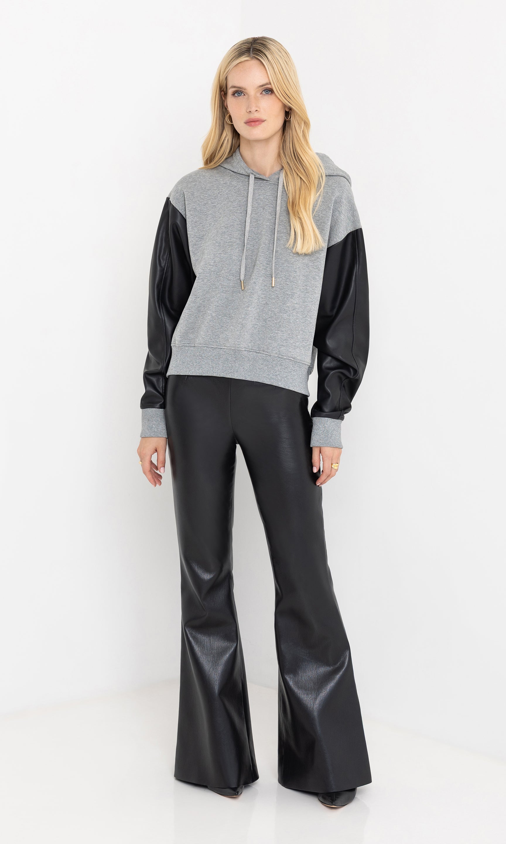 Full body front view of the lisbet vegan leather combo hoodie styled with pants.