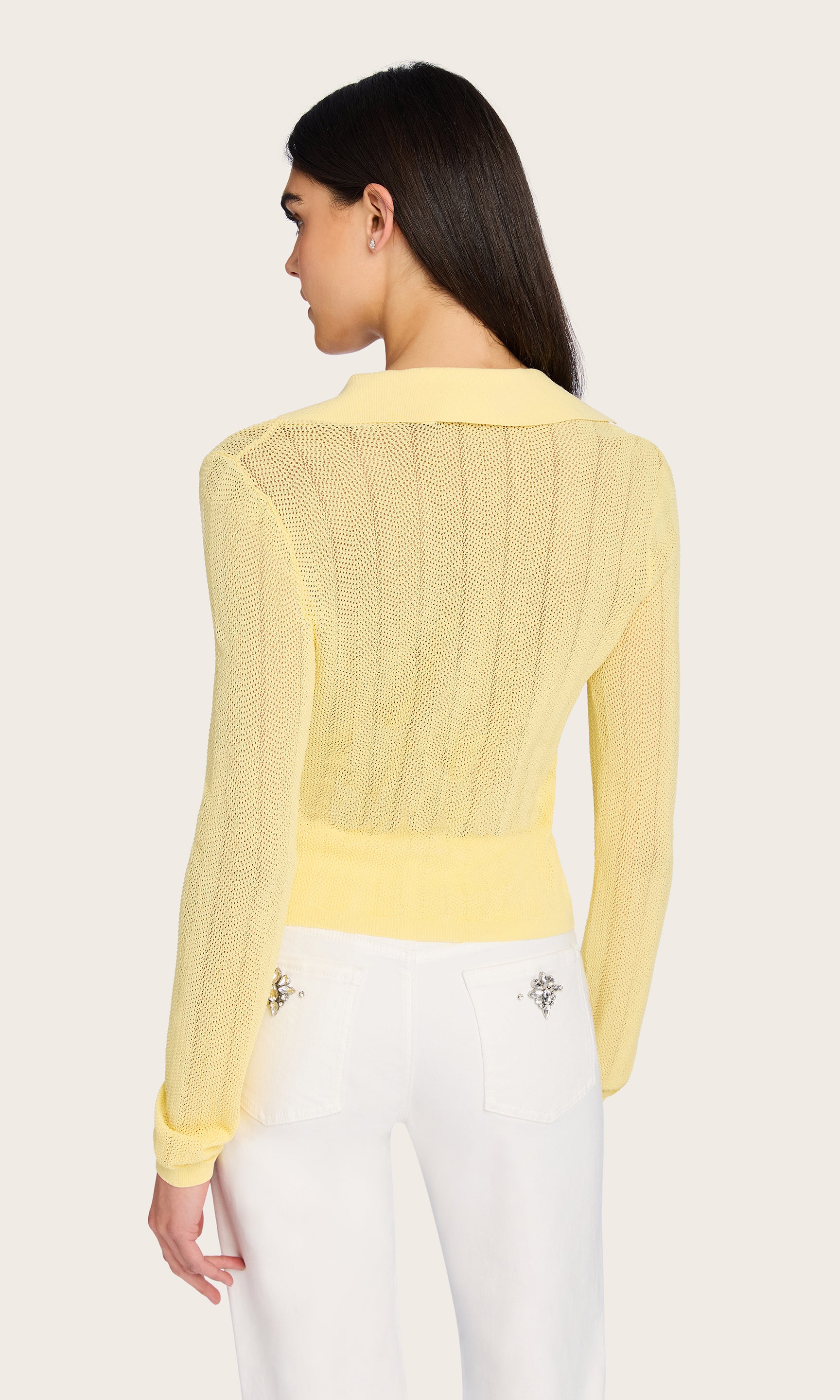 Rear view of the model wearing the Megan Pointelle Cardigan, capturing the soft yellow hue and delicate knit pattern from behind.