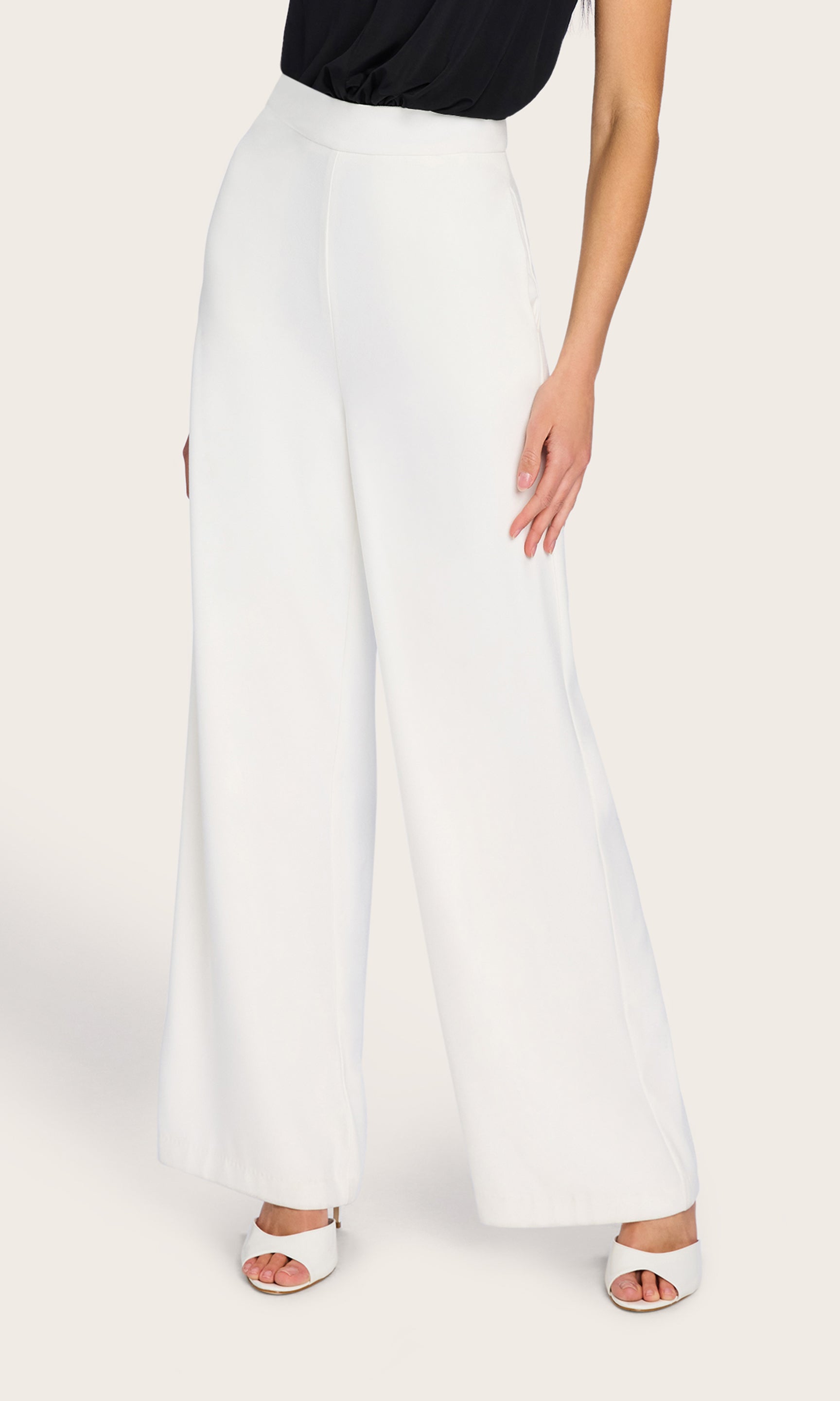 The model is seen from the front wearing the Magda Pants, showcasing their high-rise waist and elegant wide-leg silhouette paired with a black fitted top.