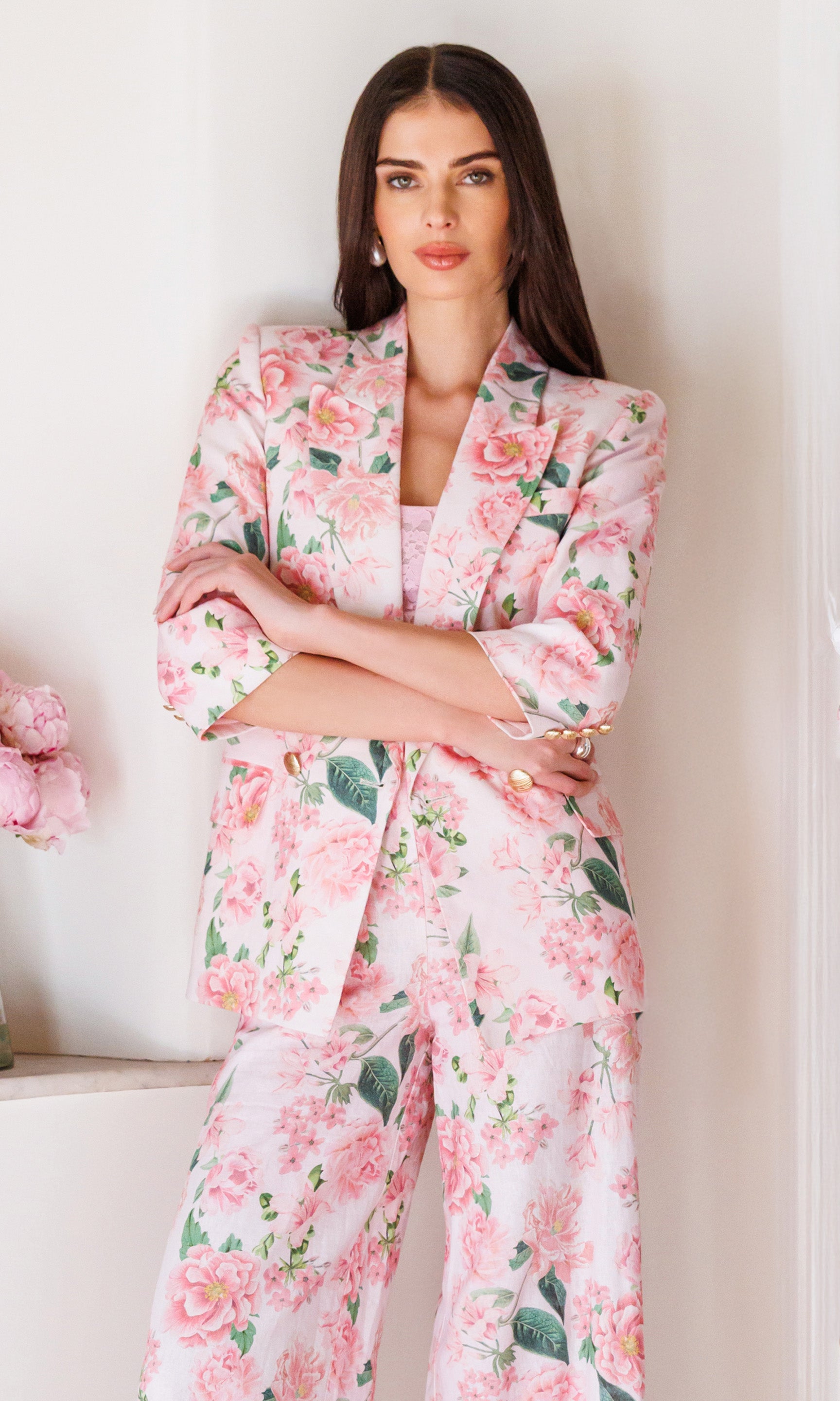 Woman wearing a pink floral suit set against a white background