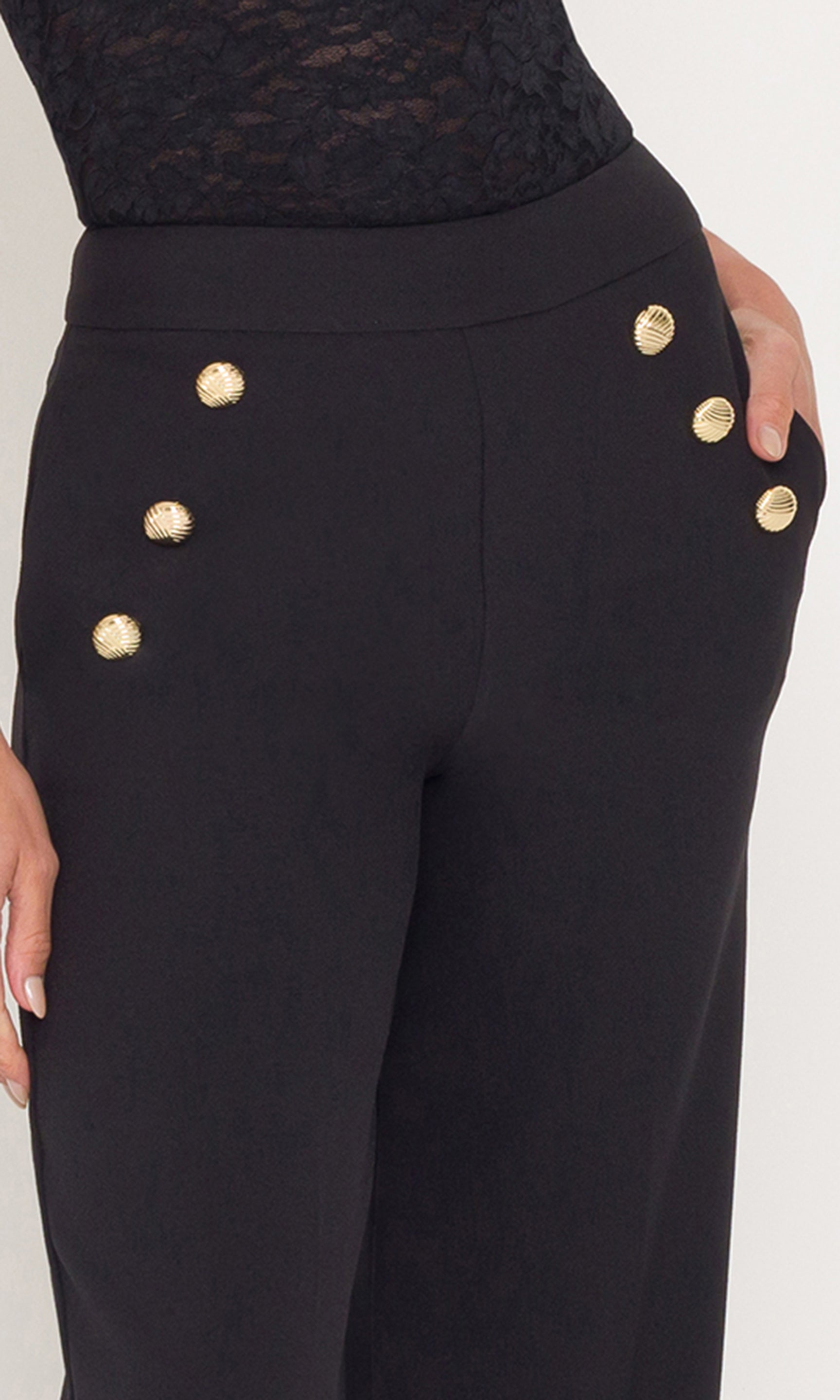 Close-up of black pants with gold buttons on a white background