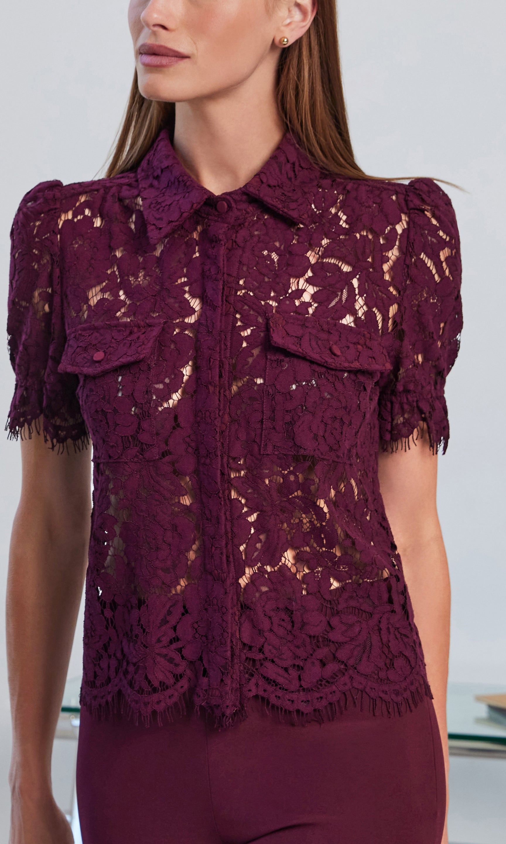 Close-up of a woman wearing a burgundy lace top with a blurred background