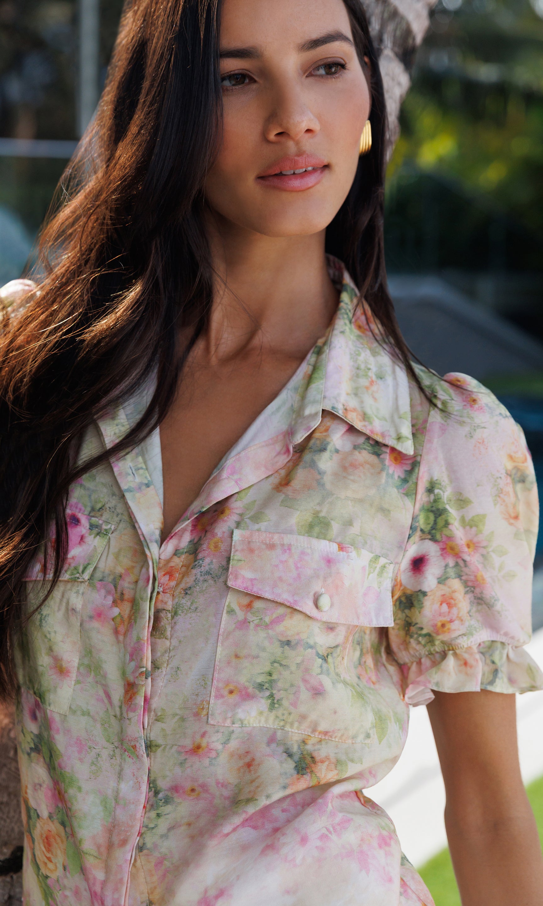 Woman wearing a floral blouse with a blurred outdoor background