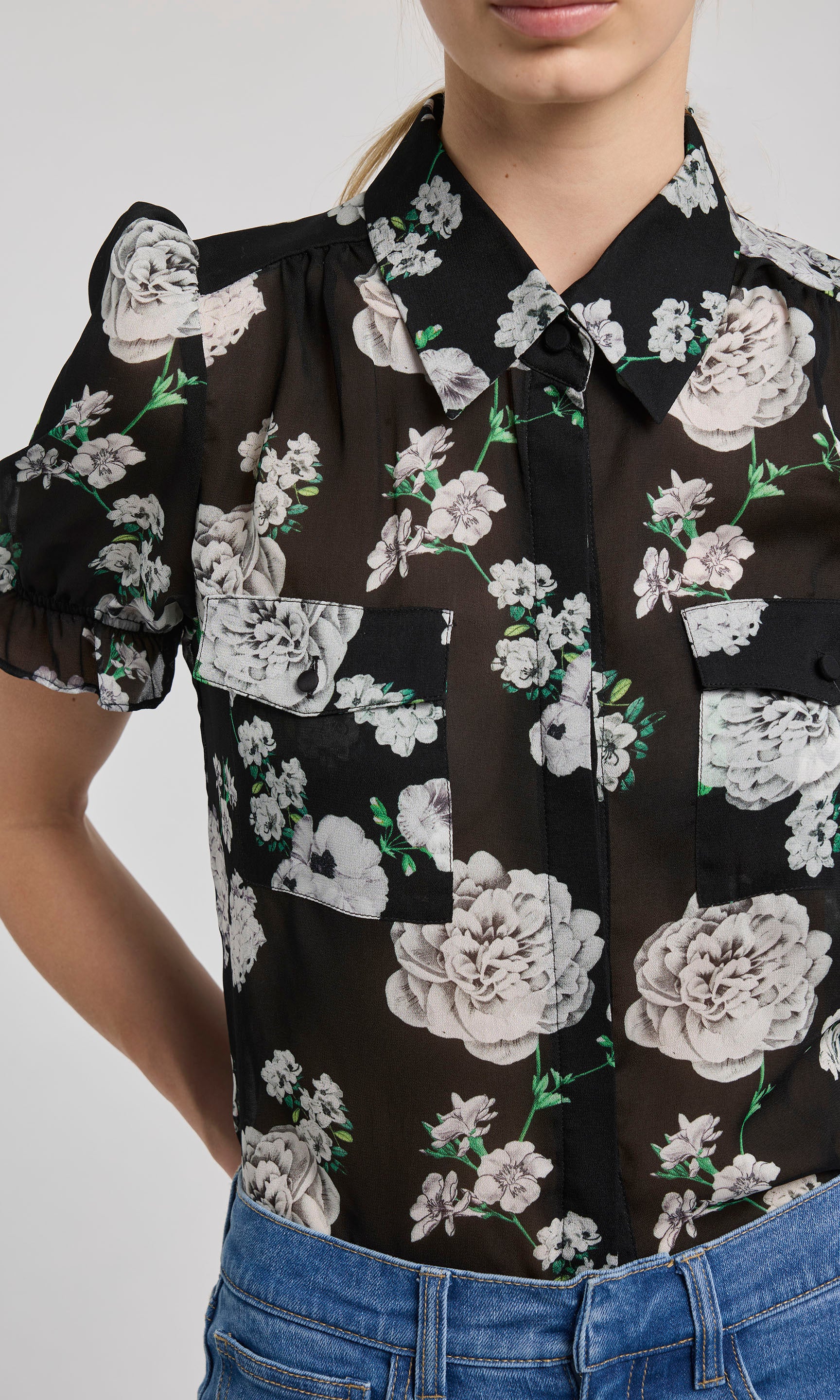 Black floral blouse with white flowers on a plain background