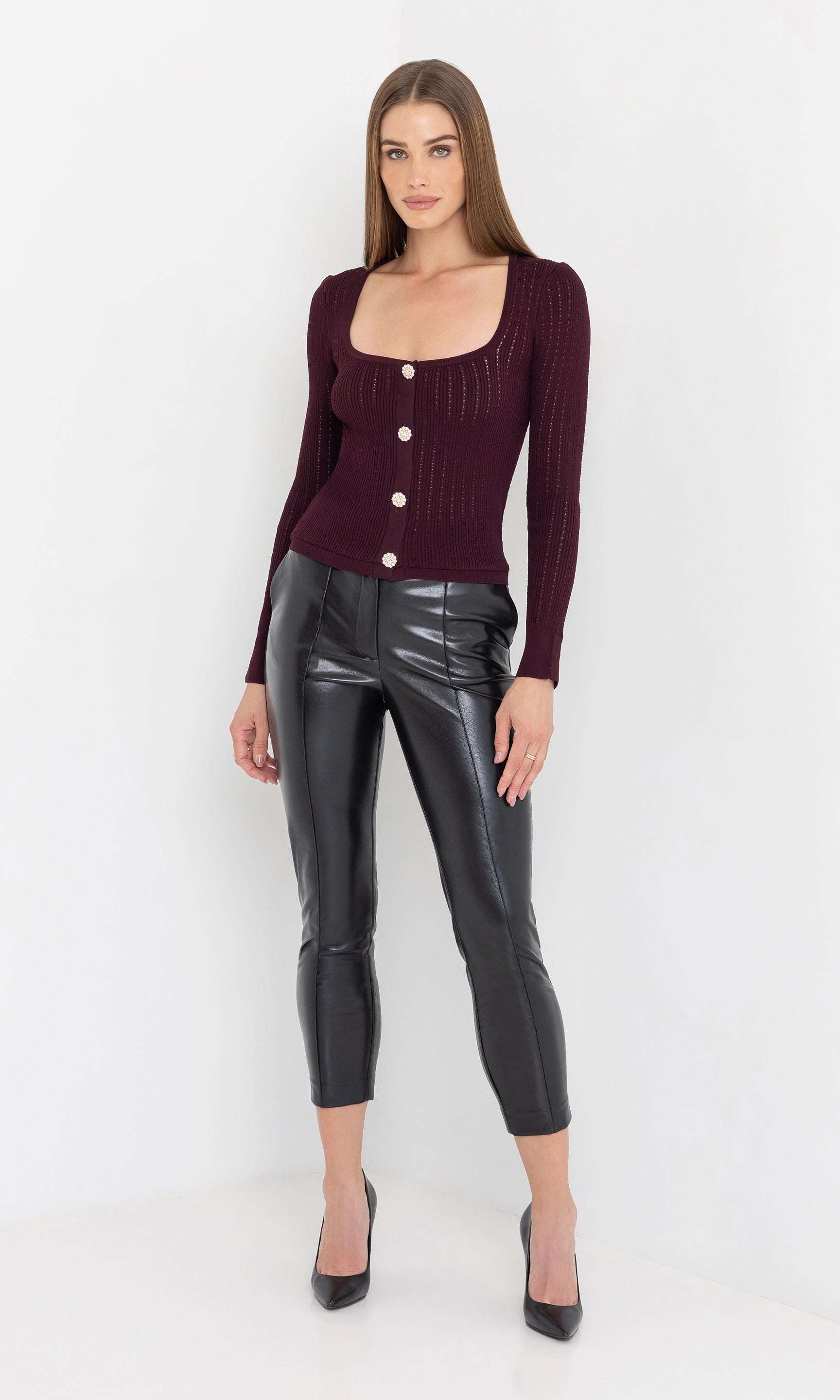 Front view of the model in the tula vegan leather pants styled with heels.