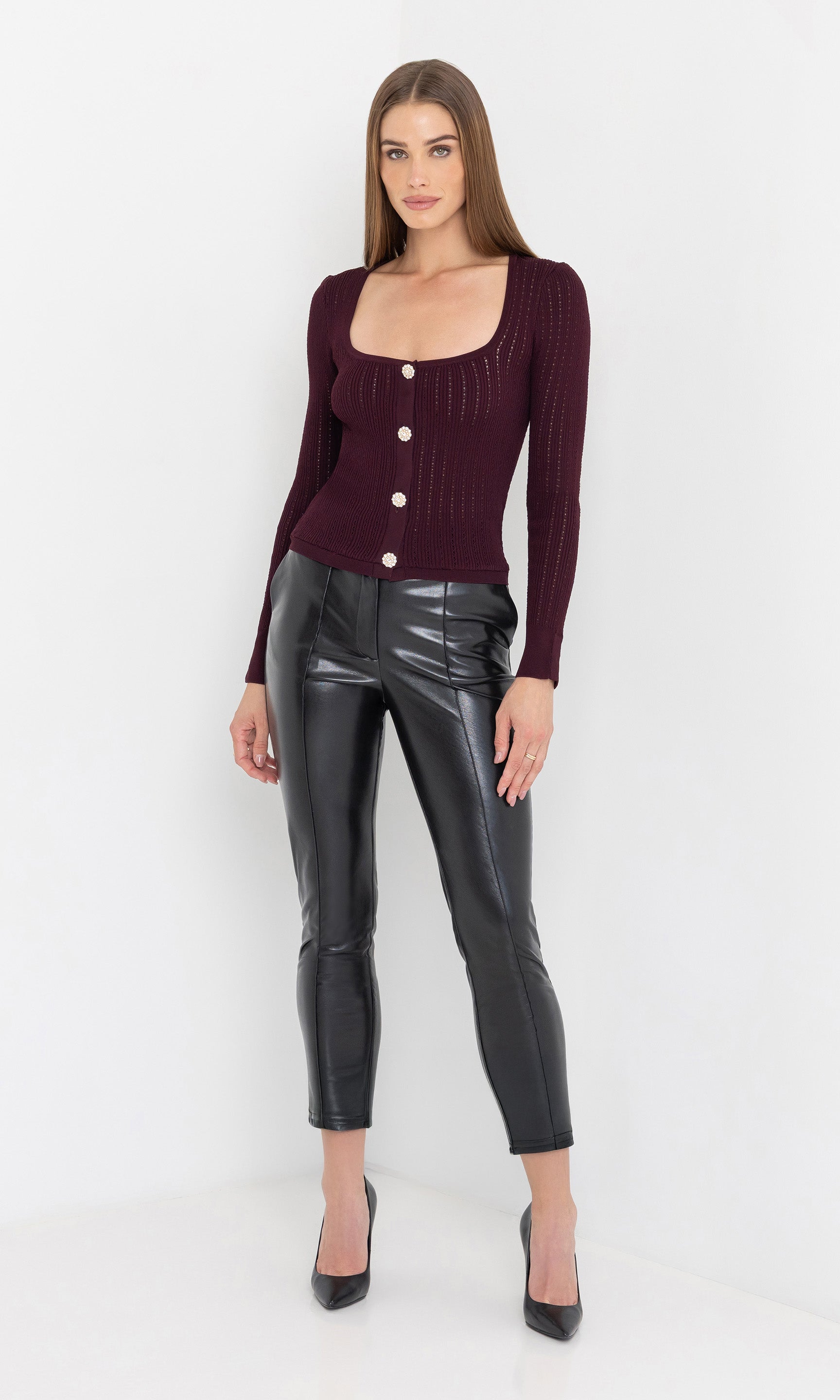 Front view of the model in the tula vegan leather pants styled with heels.