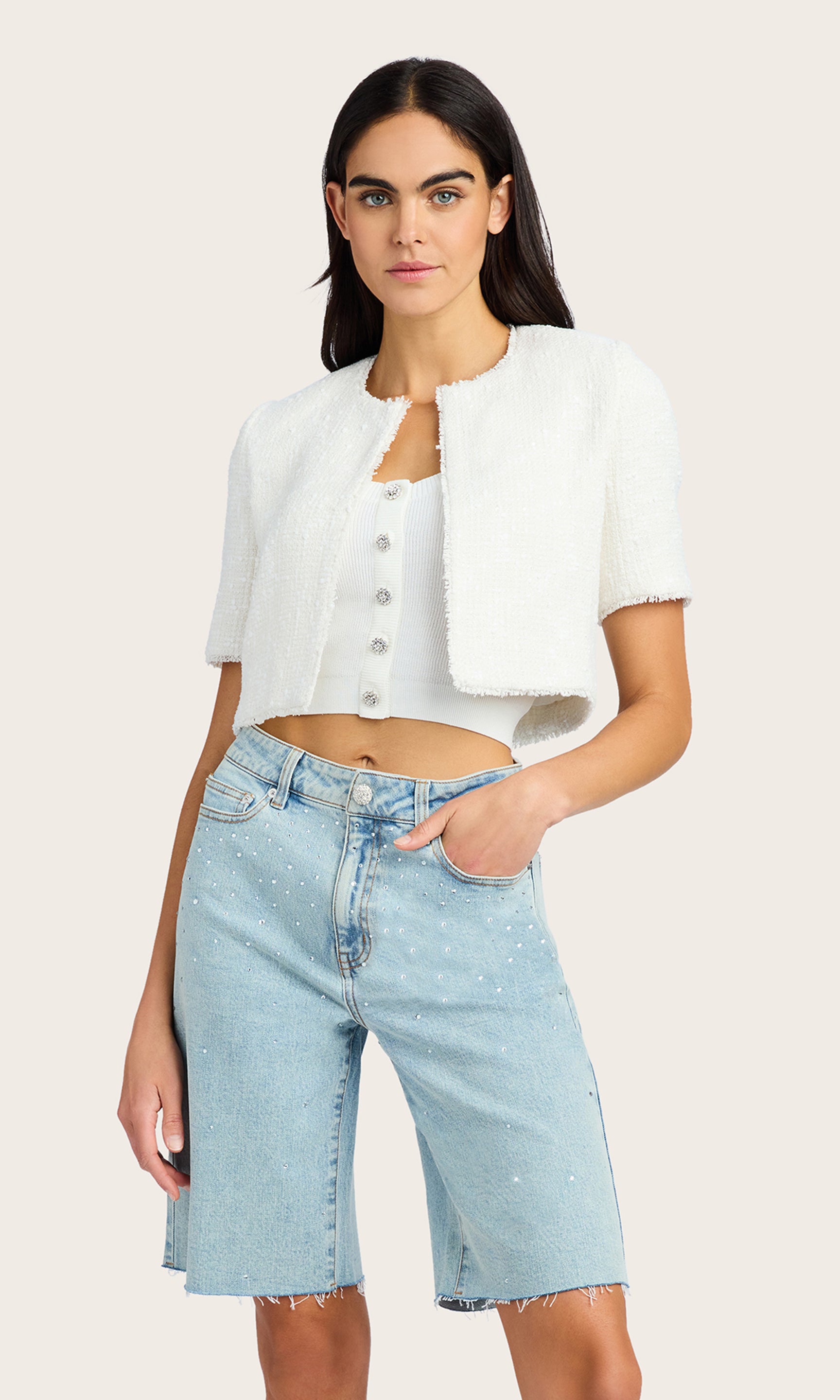 Front view of the model wearing the Nikki Tweed Jacket with light denim shorts. The cropped fit and sequin details create a chic look.