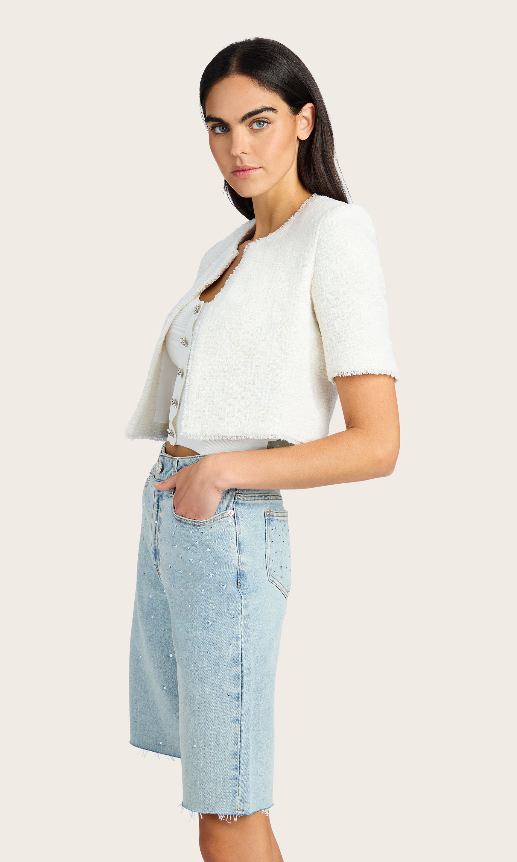 Side view of the Nikki Tweed Jacket. Highlights the short sleeves and cropped length over the shorts.