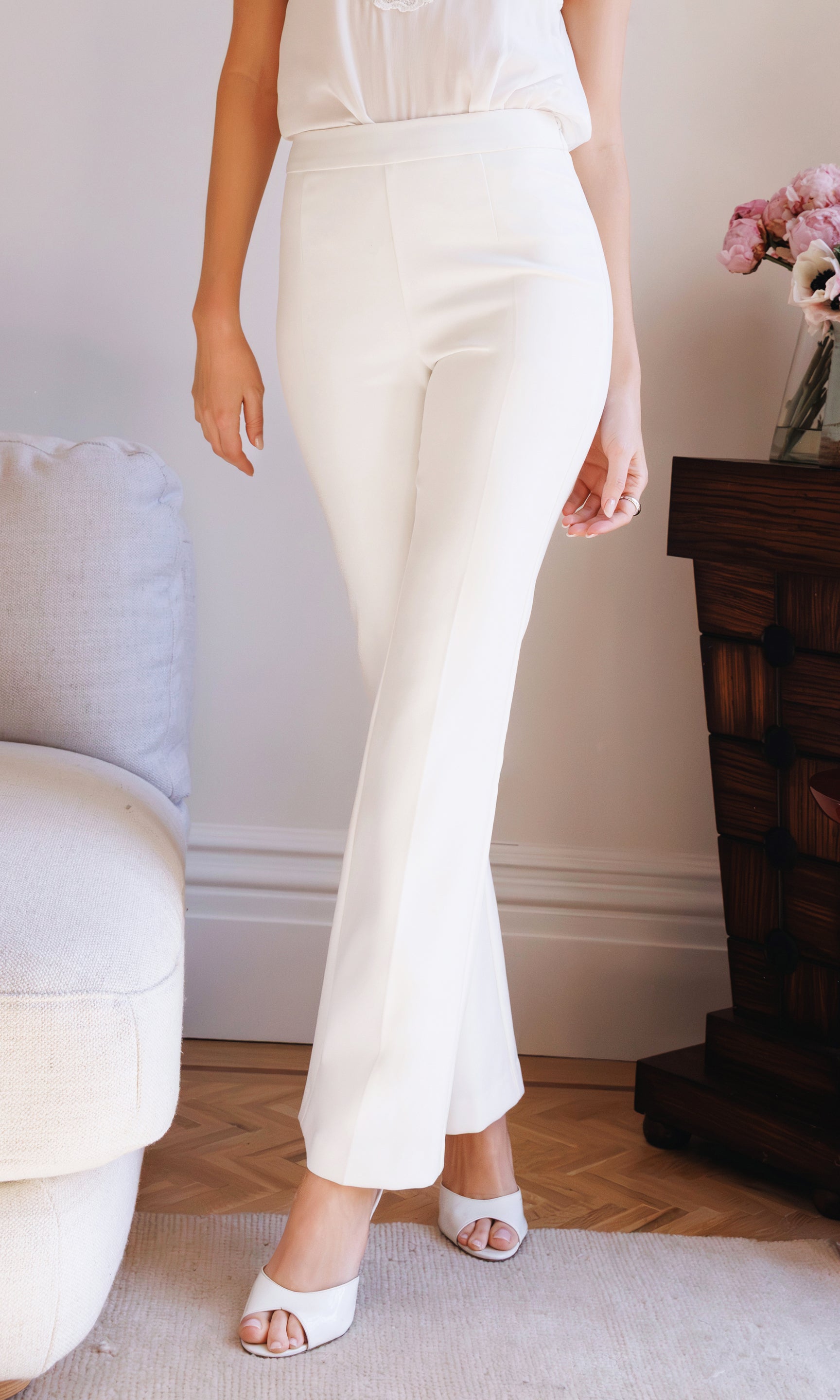 Model wears the white Nellie Crepe Pants in a side view close-up, highlighting the clean waistband and tailored fit through the leg.
