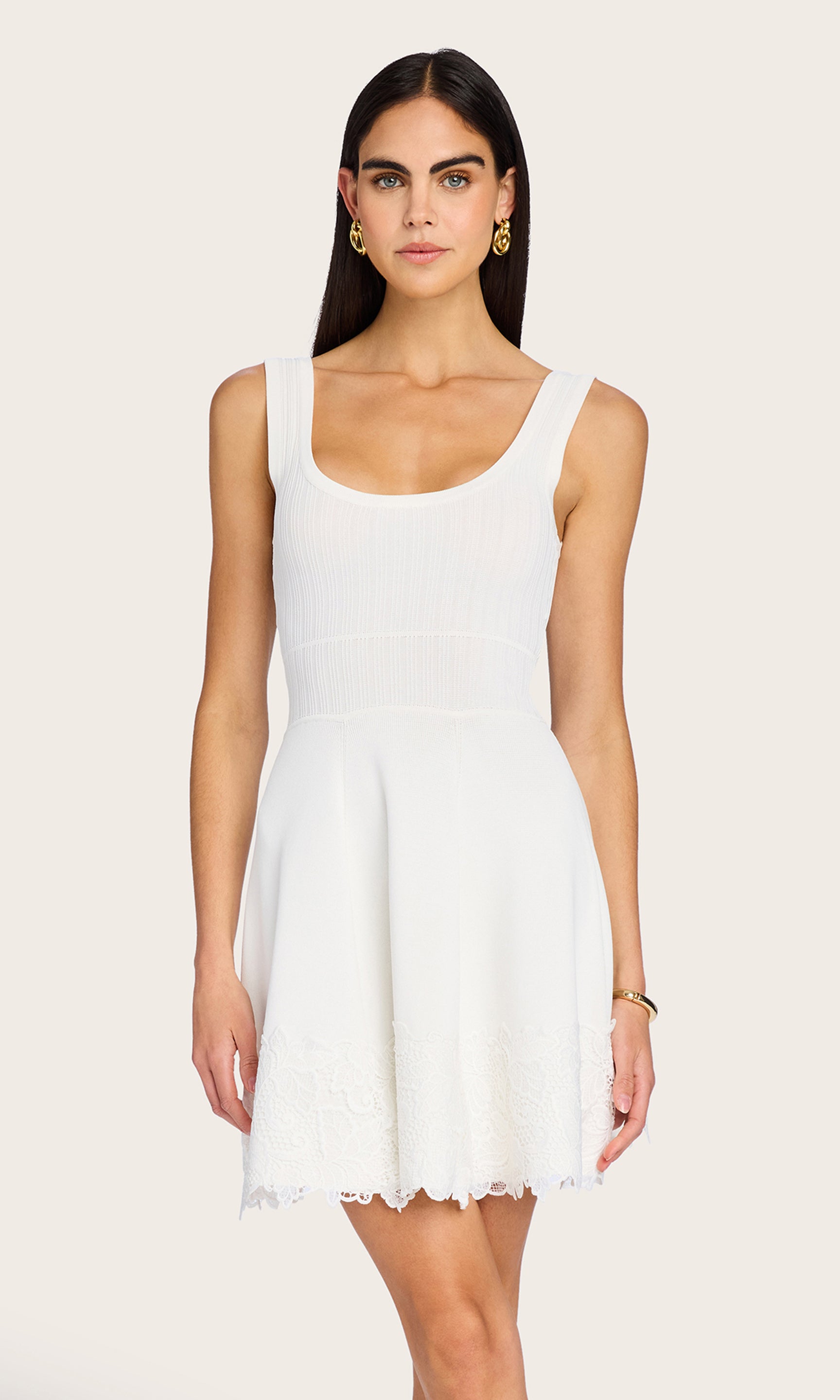 Front-facing view of the model wearing the white Orpheus Lace Combo Rib Dress, capturing its fitted bodice and flared skirt.