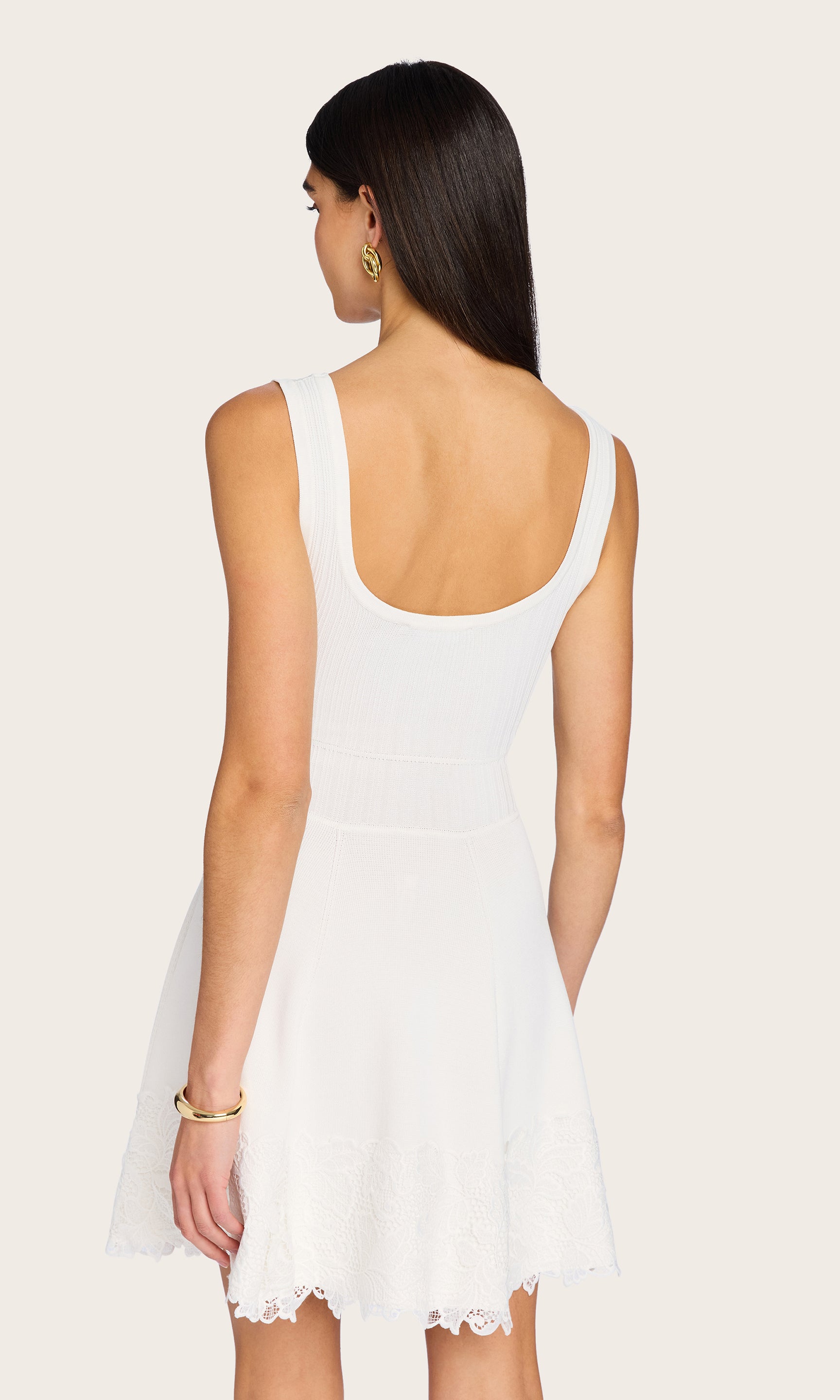 Rear view of the model styled in the white Orpheus Lace Combo Rib Dress, showing the scoop back and delicate lace hem.