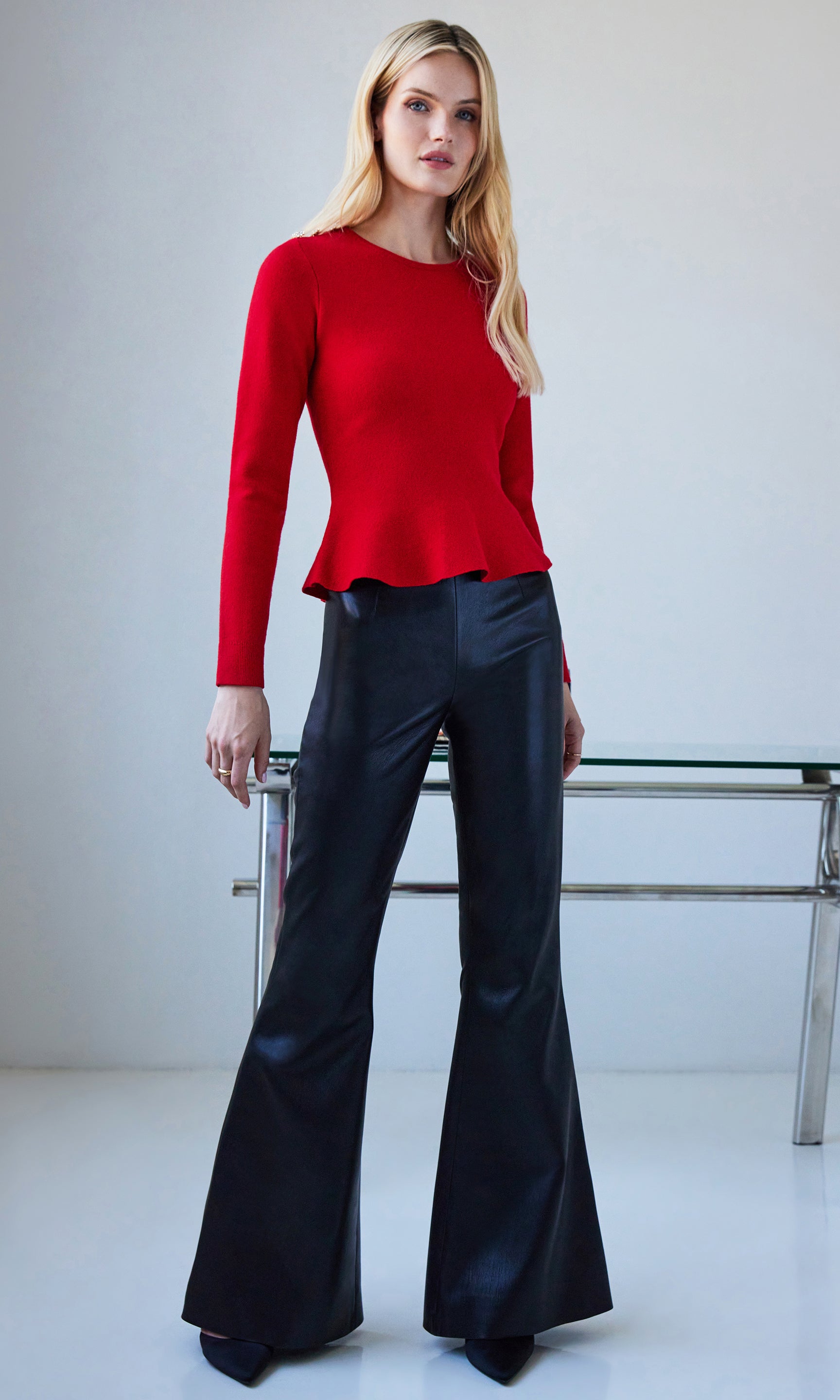 Woman wearing a red top and black pants against a white background