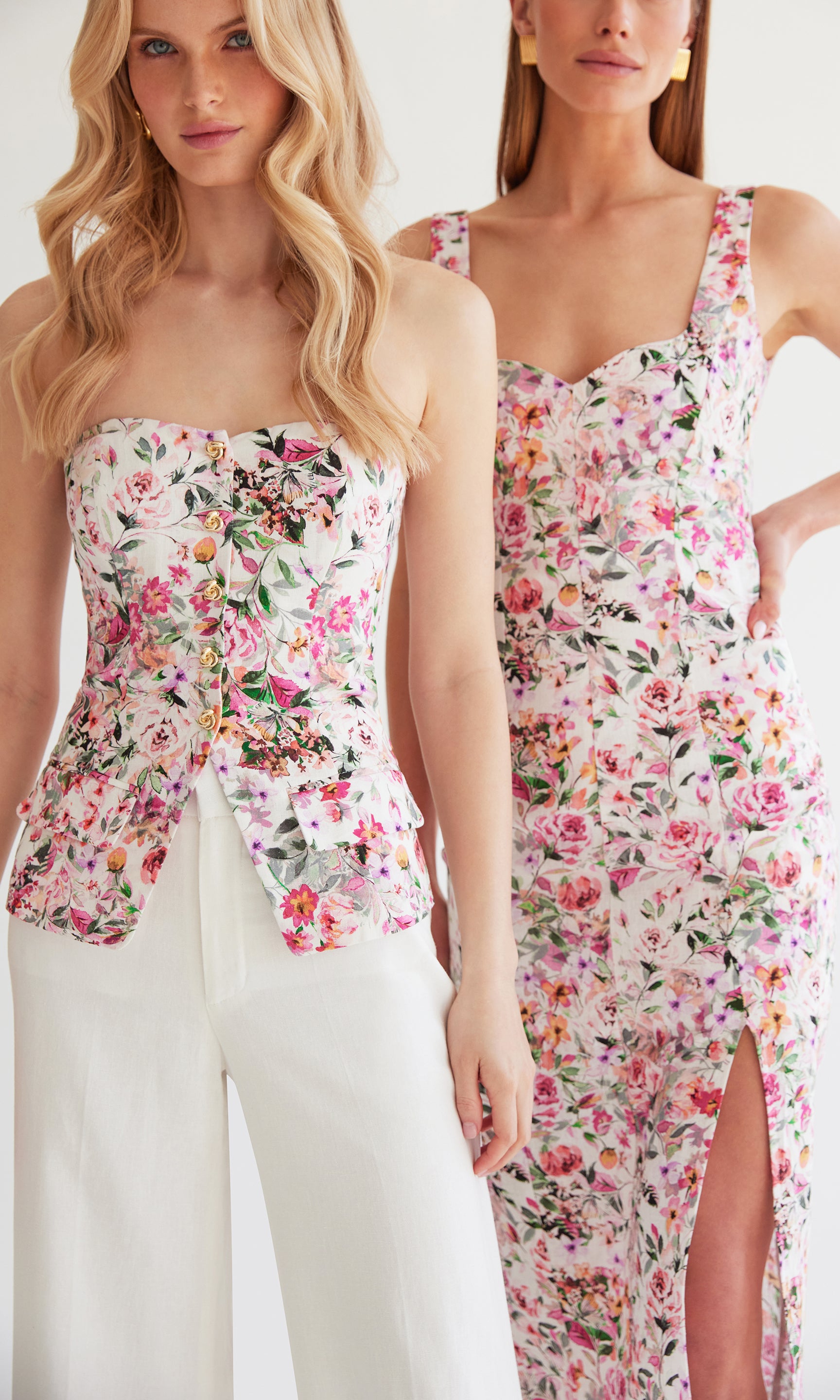 image of two models standing side by side, on the left she is wearing the Quinn vestier in white with a delicate floral design and white trousers, on the right she is wearing a midi dress with the same floral design