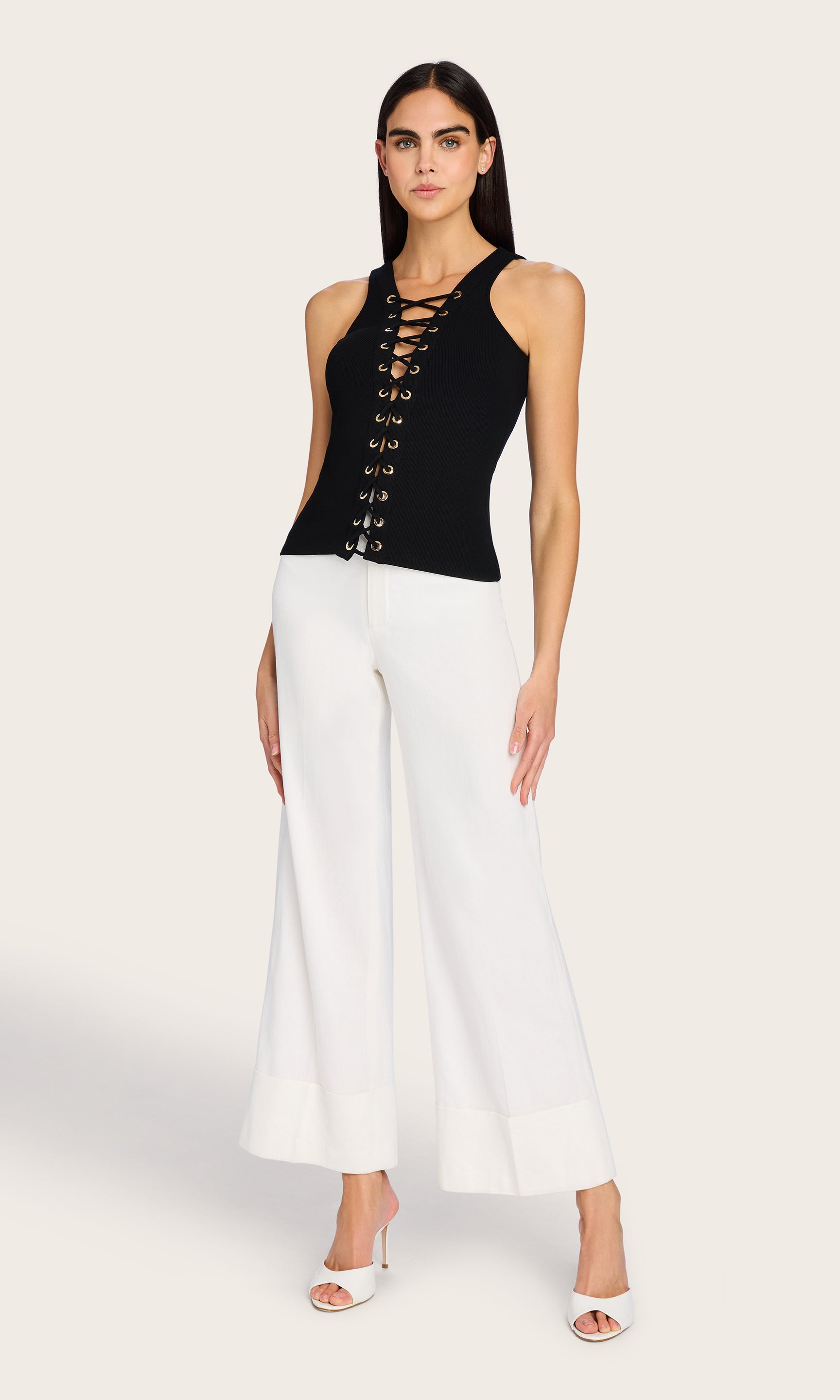 The model poses in a full-body front view wearing the Rashelle Lace-Up Top, creating a sleek monochrome look with wide-leg pants.