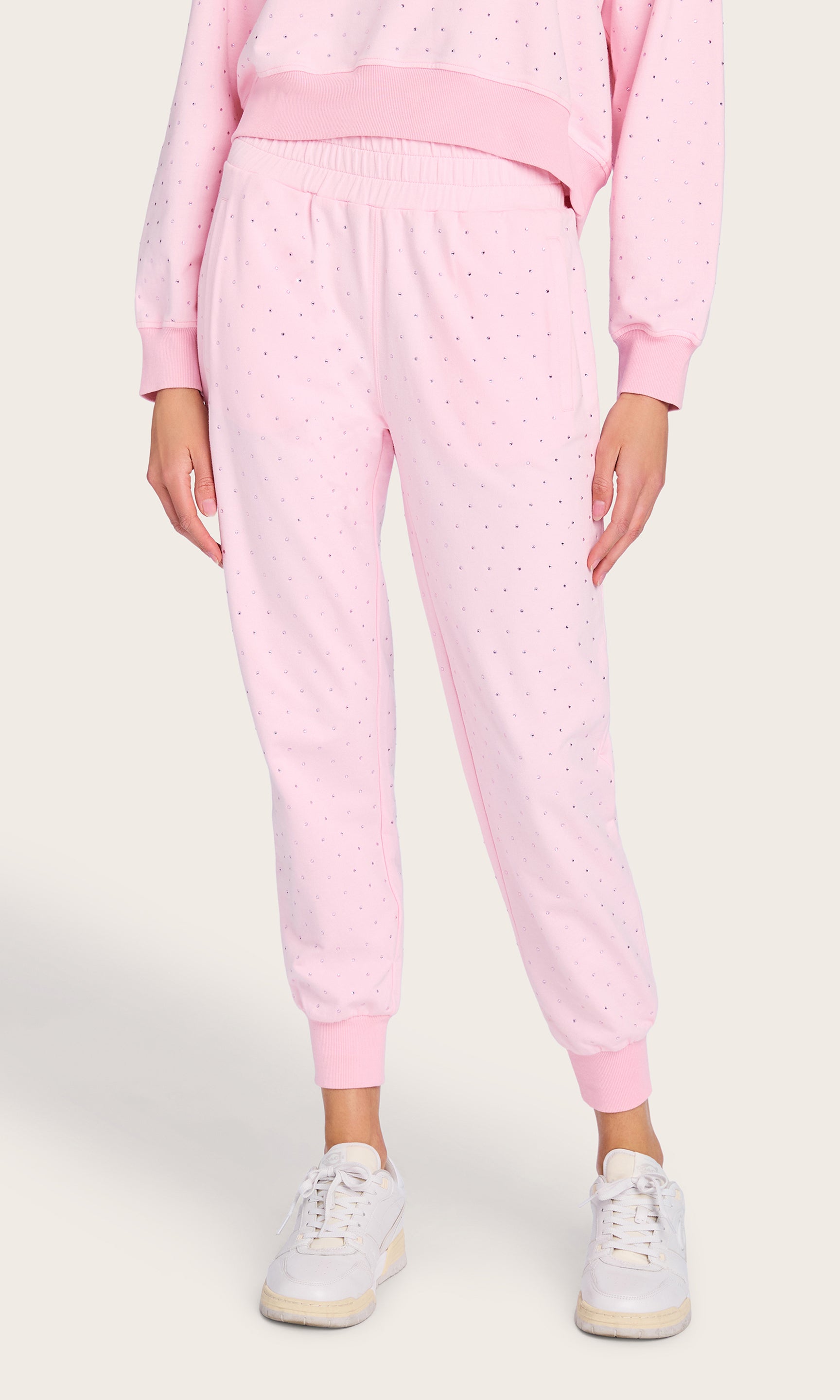 Front view of the Ruel Crystal Sweatpants styled with a matching pink sweatshirt and sneakers, highlighting the tapered silhouette and soft cotton finish