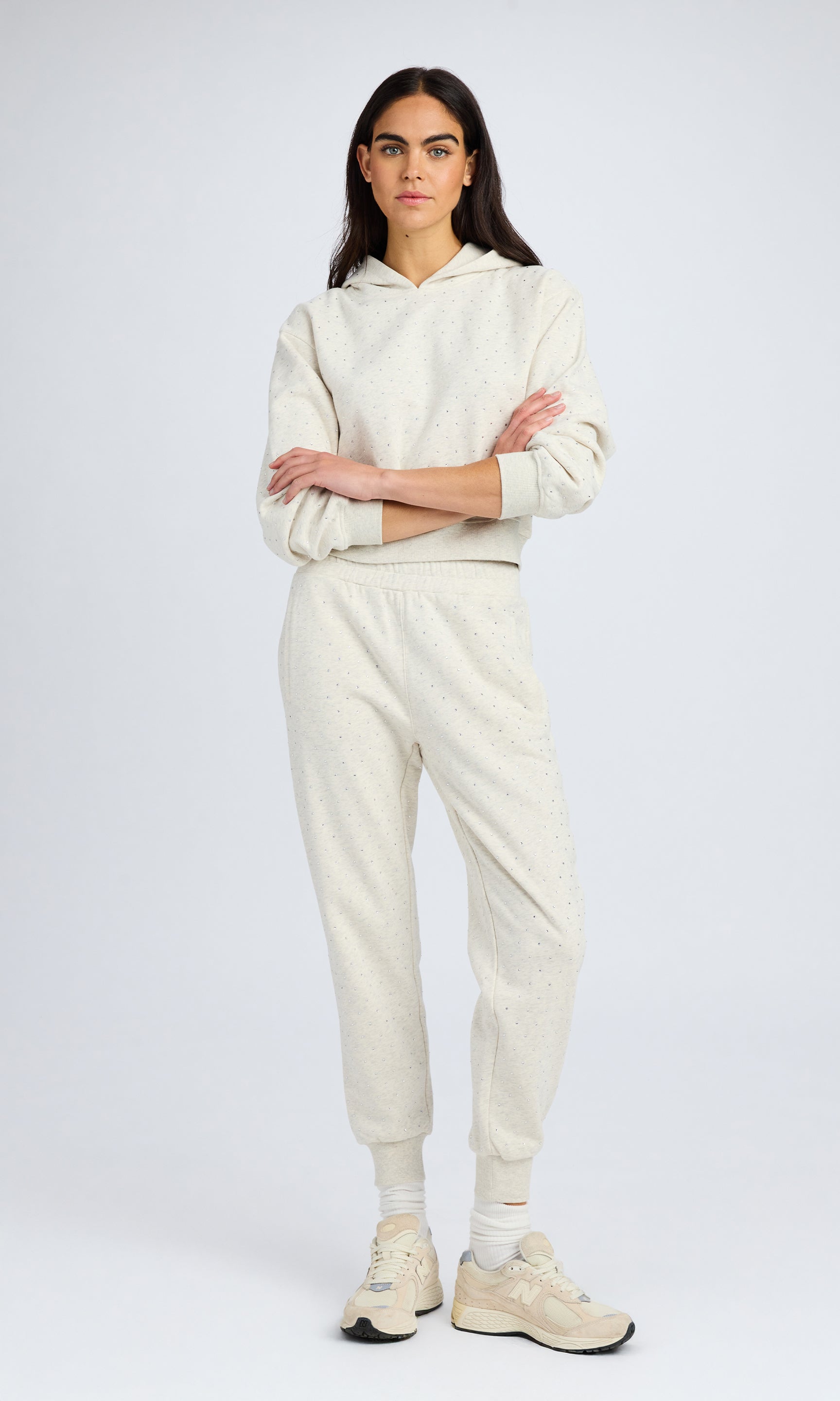 model stands wearing a light grey matching sweatshirt and sweatpants with all over crystals