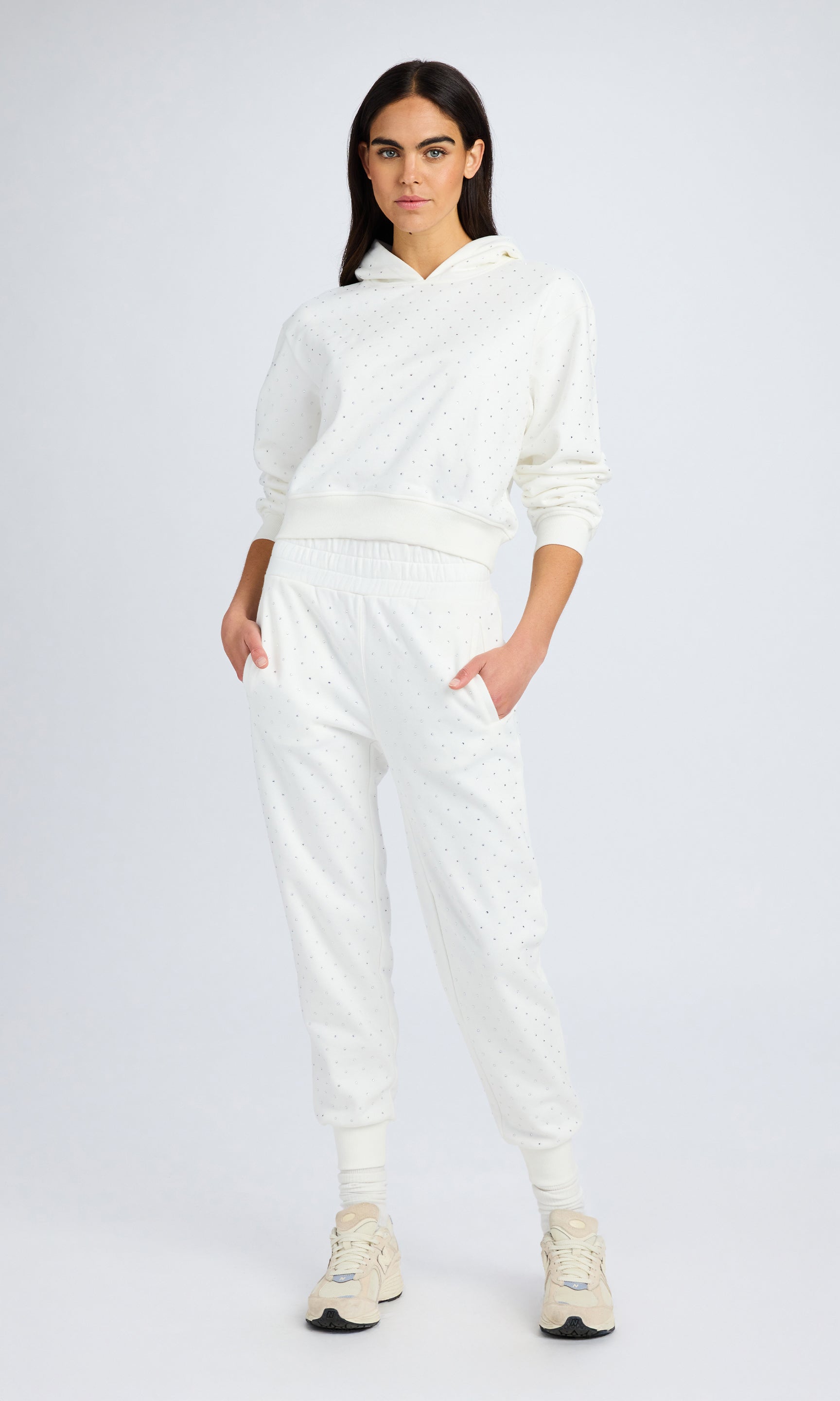 Model stands wearing a white crystal sweatshirt and matching sweatpants.