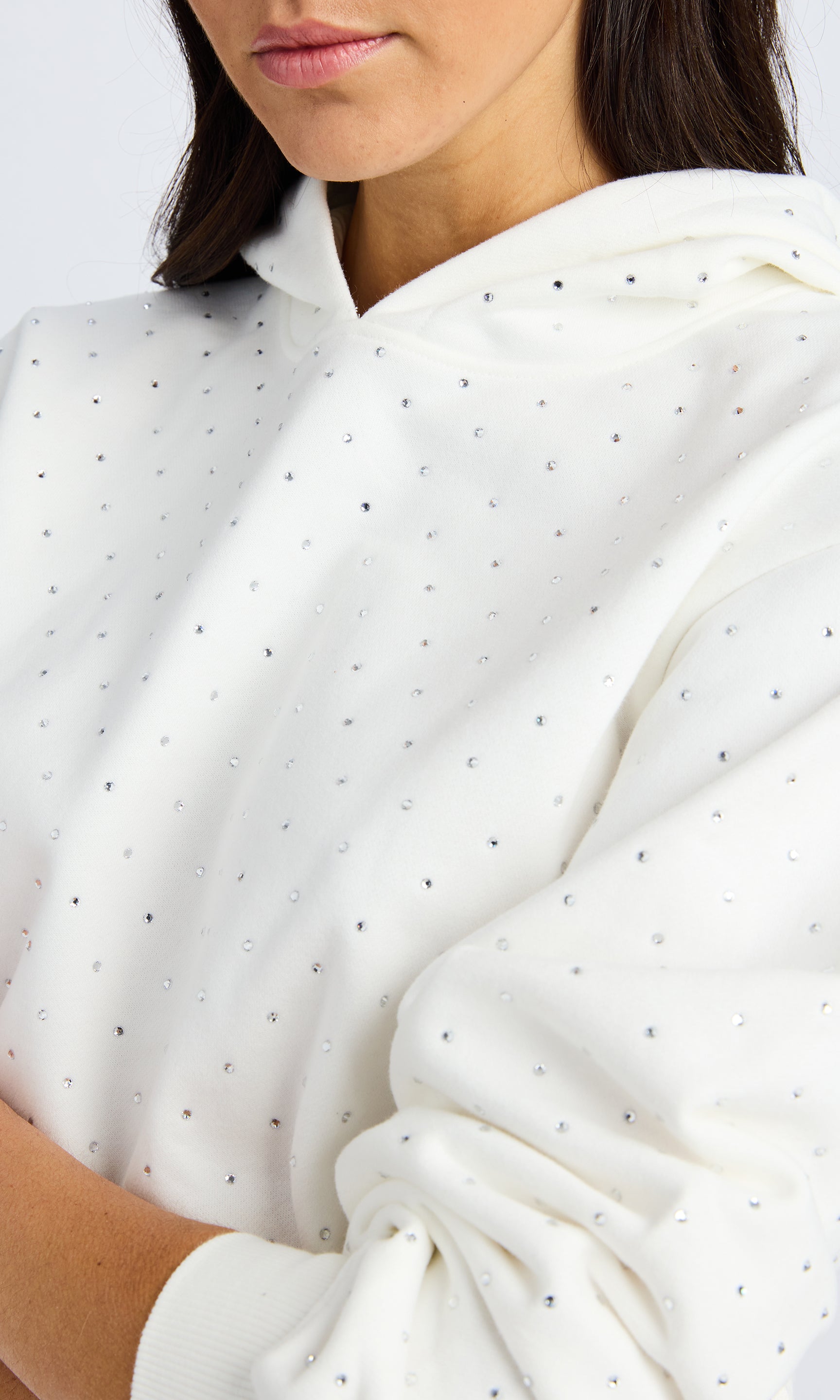 Close up image of a white hooded sweatshirt with crystals.