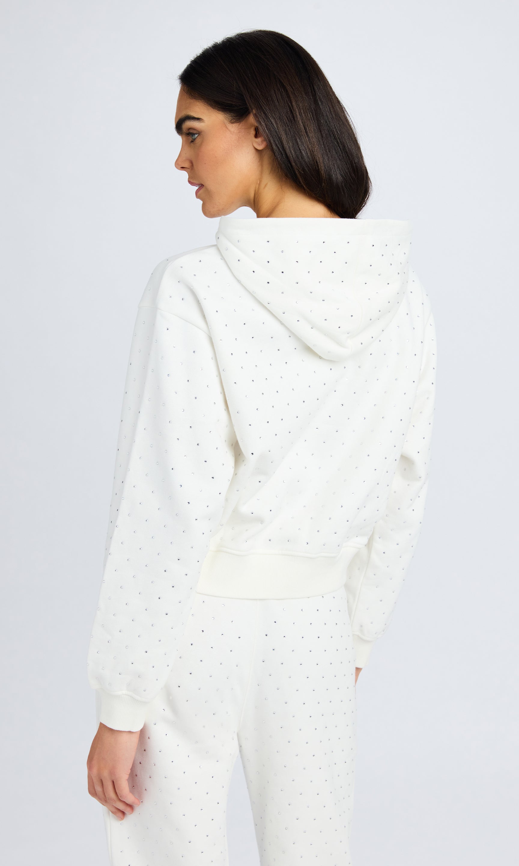 Rear view of model wearing a white hooded sweatshirt with matching sweatpants.