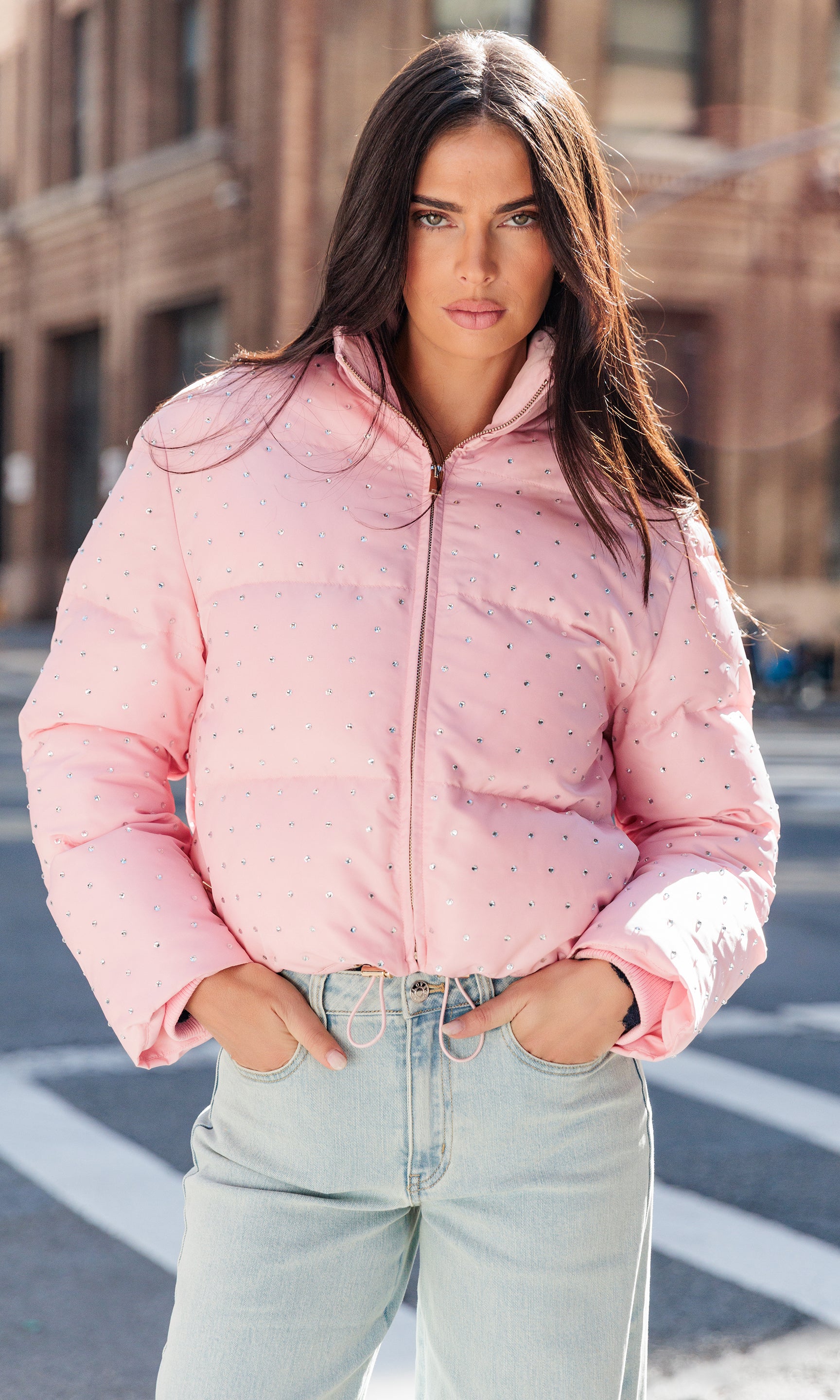 Woman wearing a pink puffer jacket on a city street