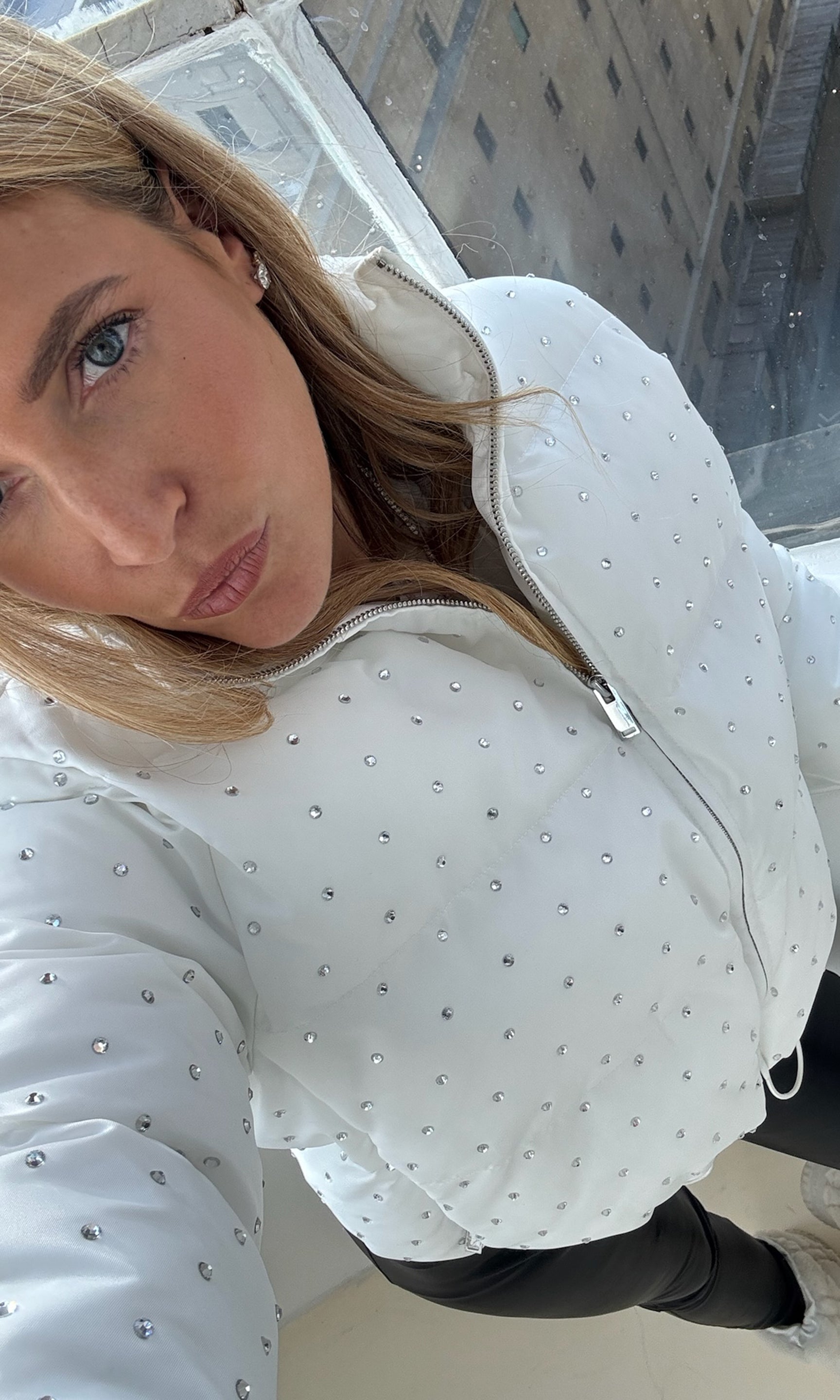 Woman wearing a white jacket with crystal embellishments in an urban setting