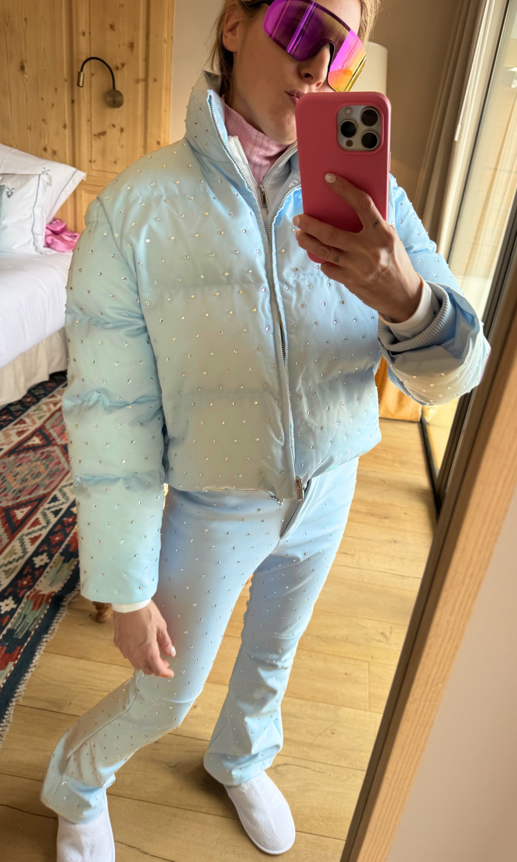 Person taking a mirror selfie wearing a light blue puffer jacket and pants indoors.